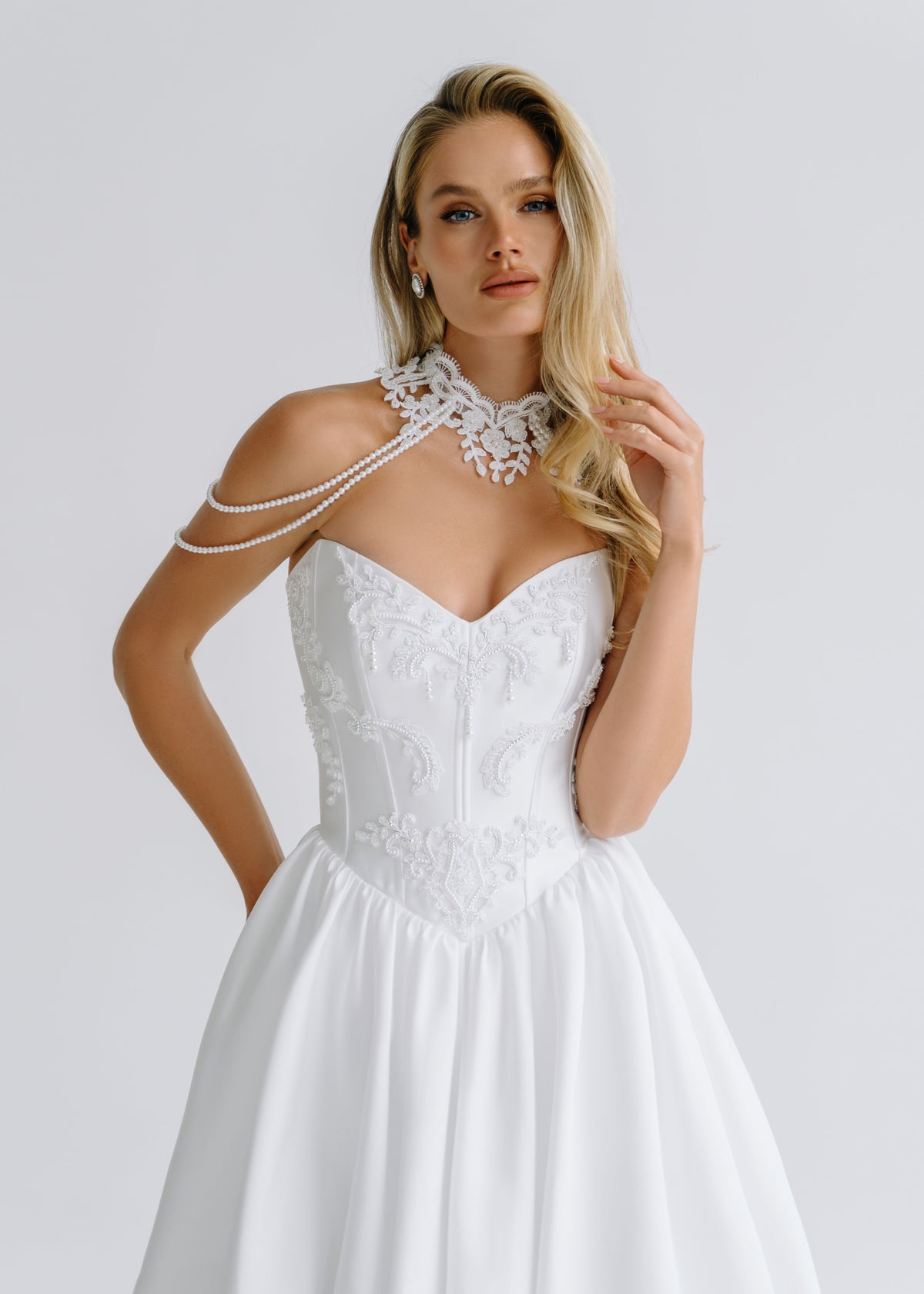 Close-up of a lace collar with chain-draped straps over an embroidered bodice