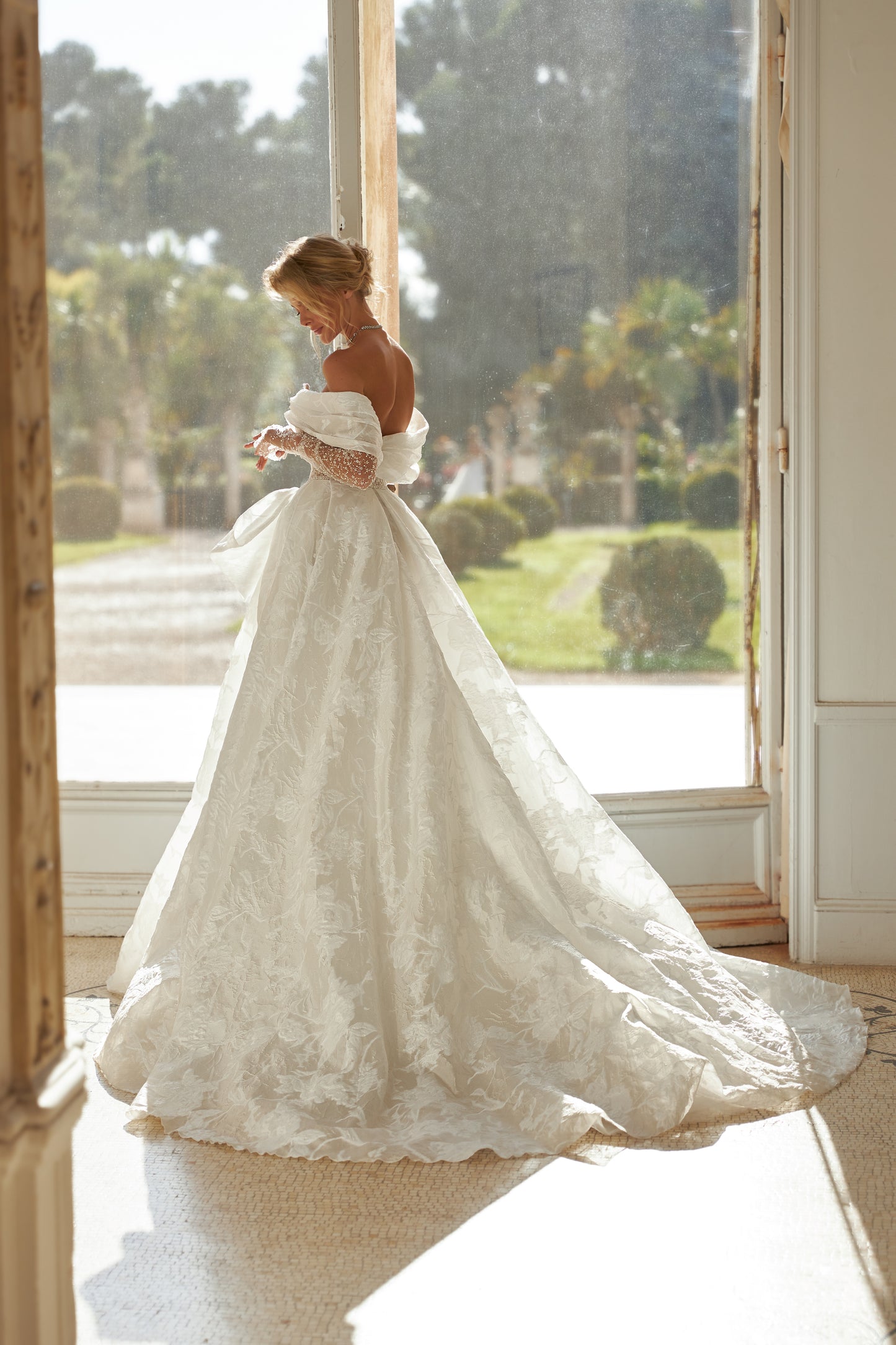 A-line wedding dress with open back, illusion sleeves.