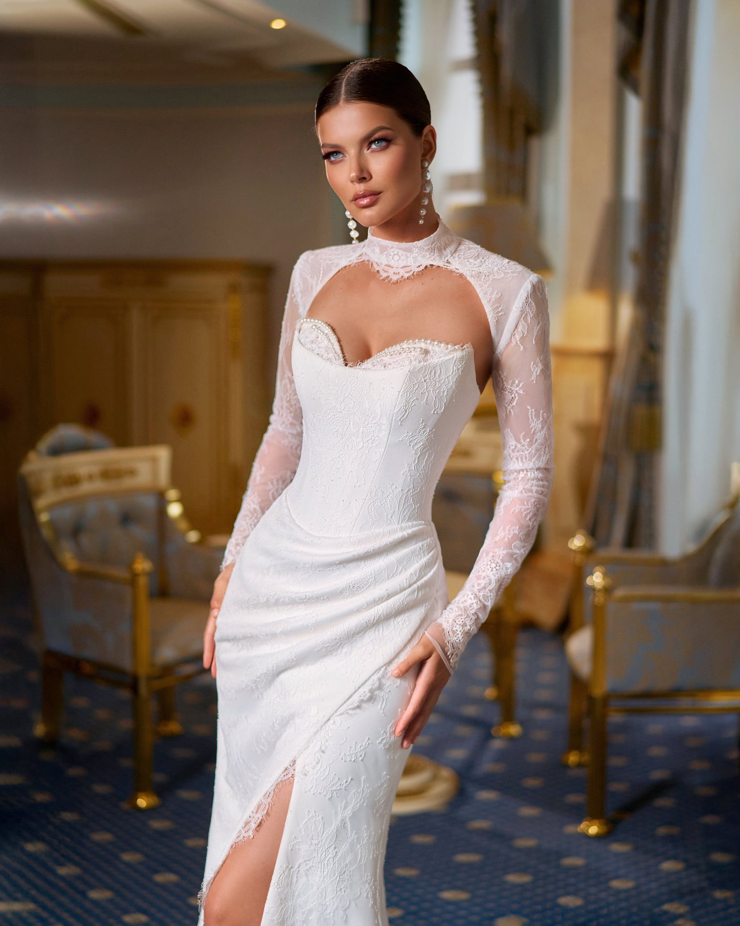 Bride in fitted lace wedding dress with sweetheart neckline, removable long-sleeve lace bolero, thigh-high slit, and chapel train.