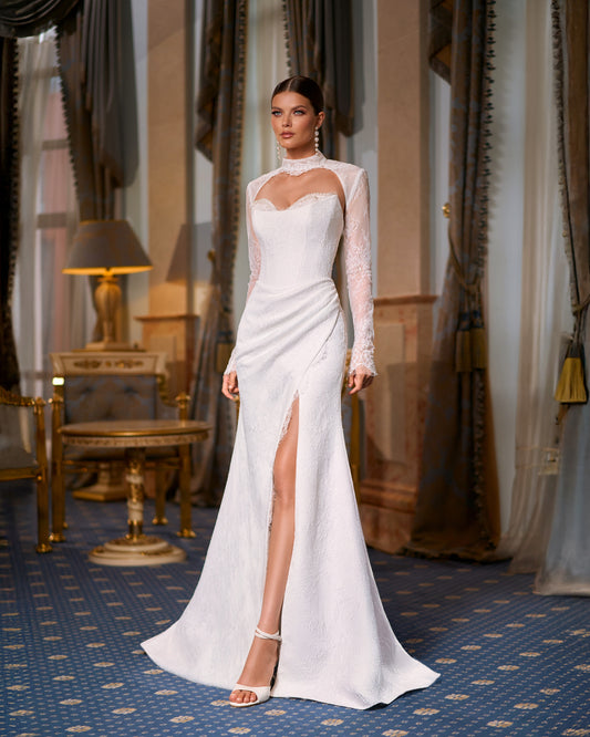 Bride in fitted lace wedding dress with sweetheart neckline, removable long-sleeve lace bolero, thigh-high slit, and chapel train.