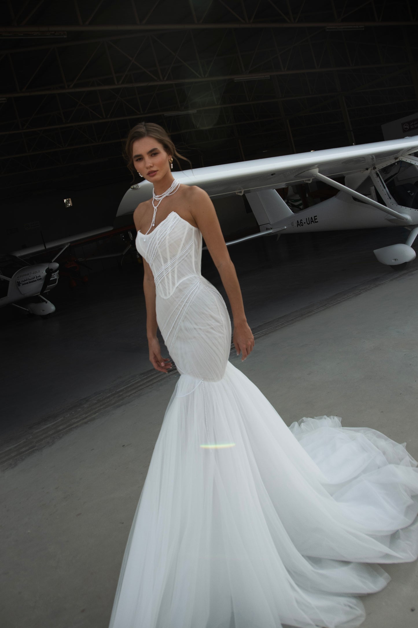 Strapless mermaid wedding dress with corrugated tulle, pearl detailing, fit and flare silhouette, and sweeping fishtail train for striking modern bridal look