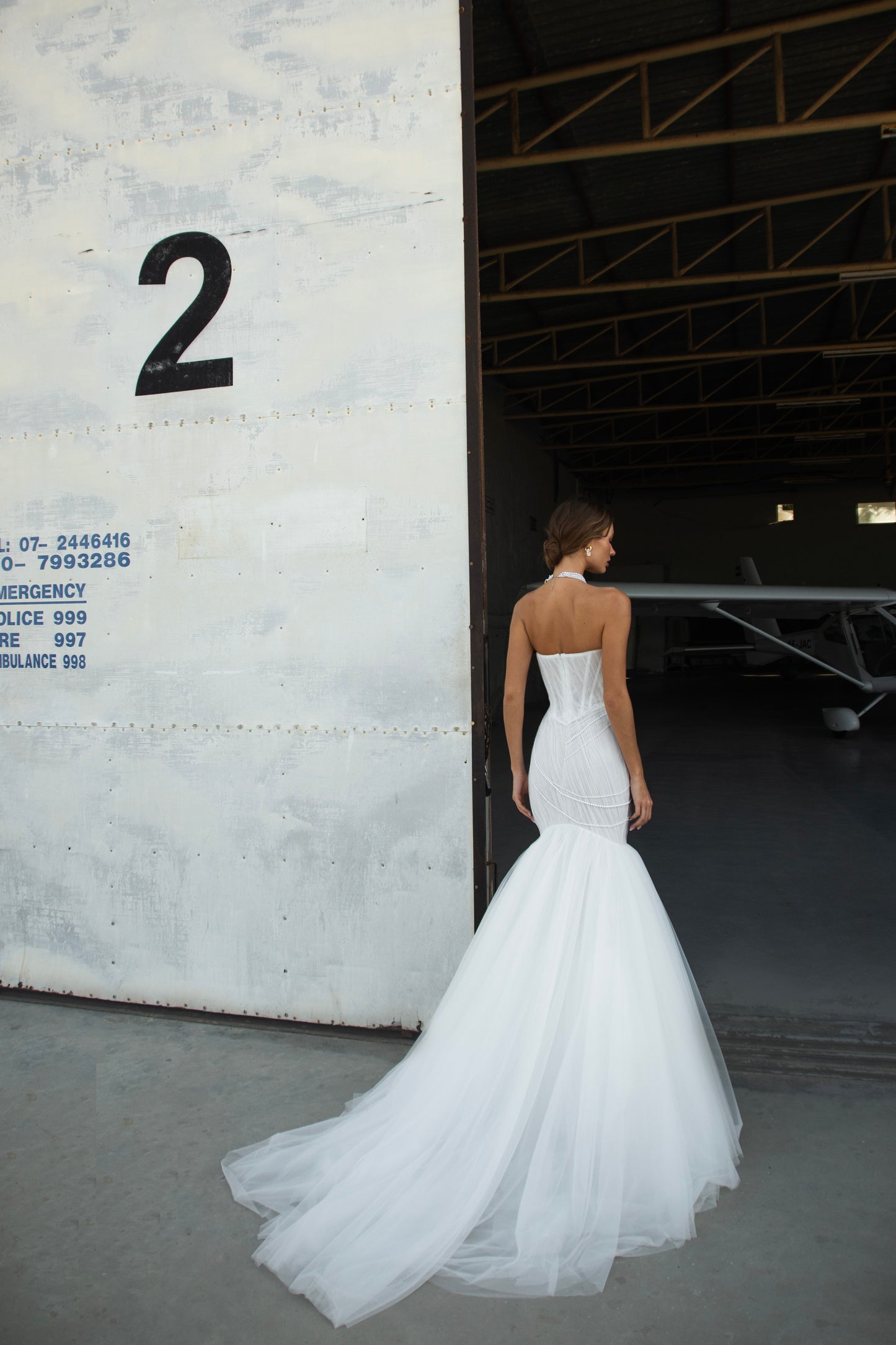 Strapless mermaid wedding dress with corrugated tulle, pearl detailing, fit and flare silhouette, and sweeping fishtail train for striking modern bridal look