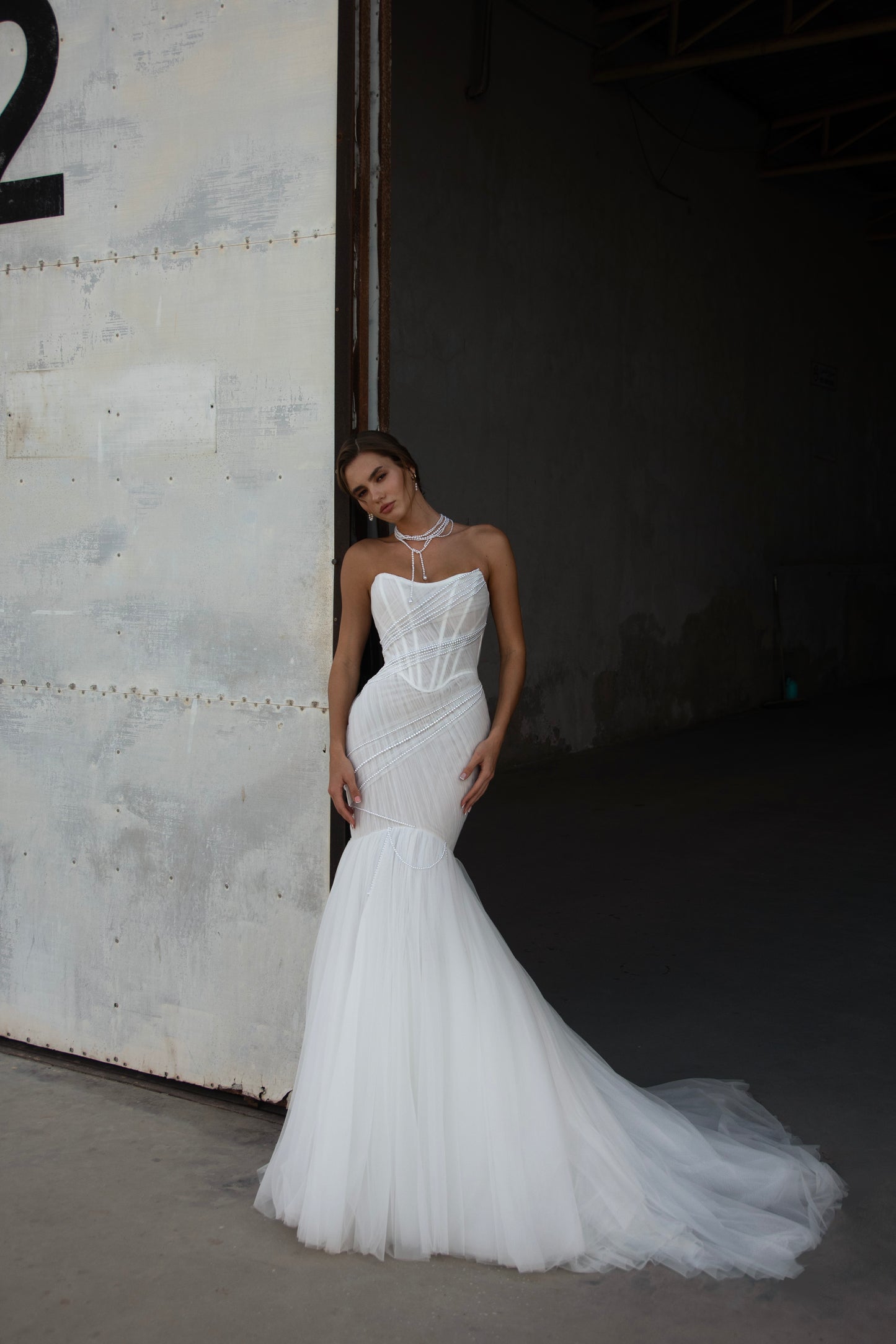 Strapless mermaid wedding dress with corrugated tulle, pearl detailing, fit and flare silhouette, and sweeping fishtail train for striking modern bridal look