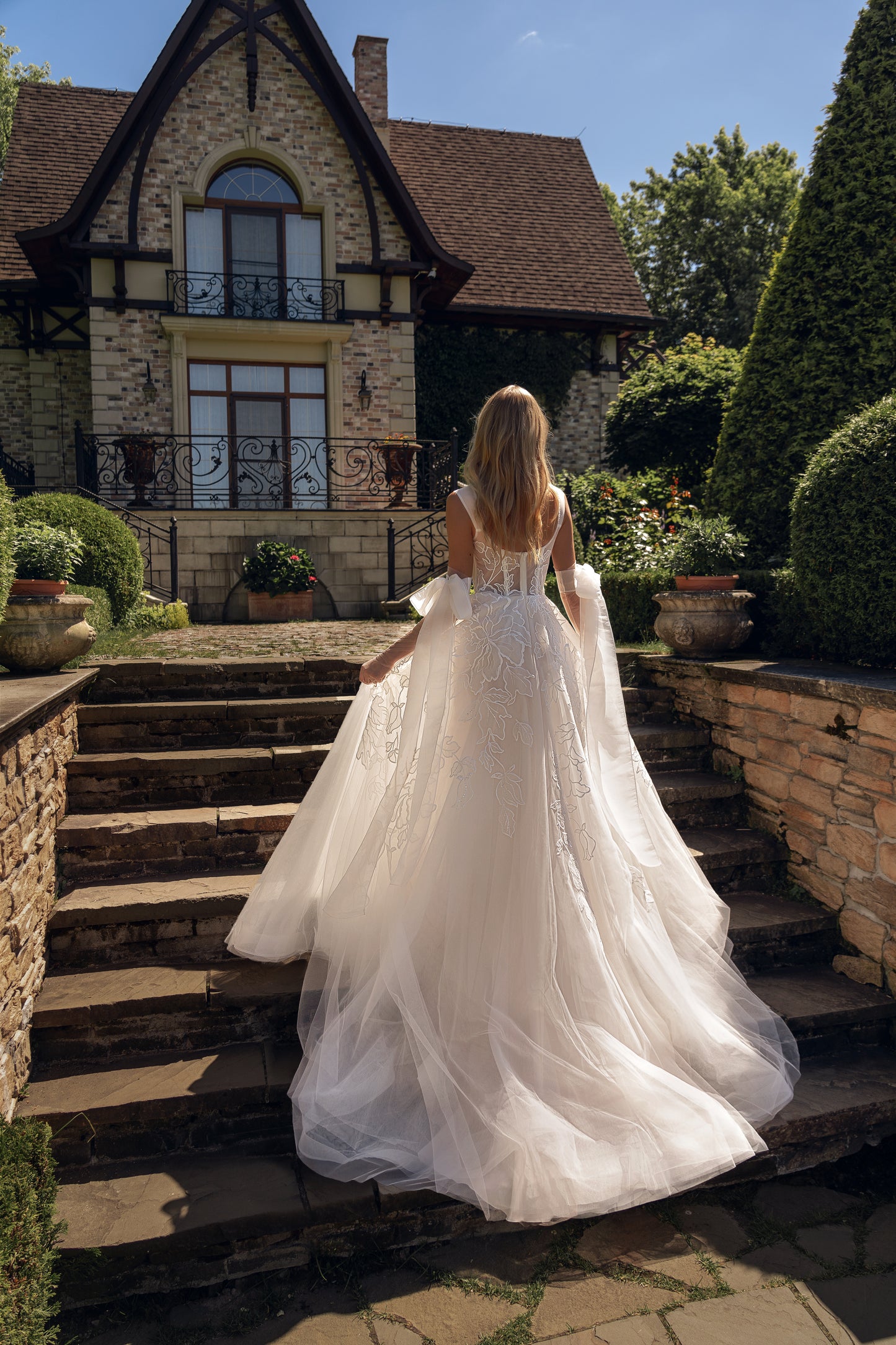 Sleeveless wedding dress with tulle gloves and lace details.