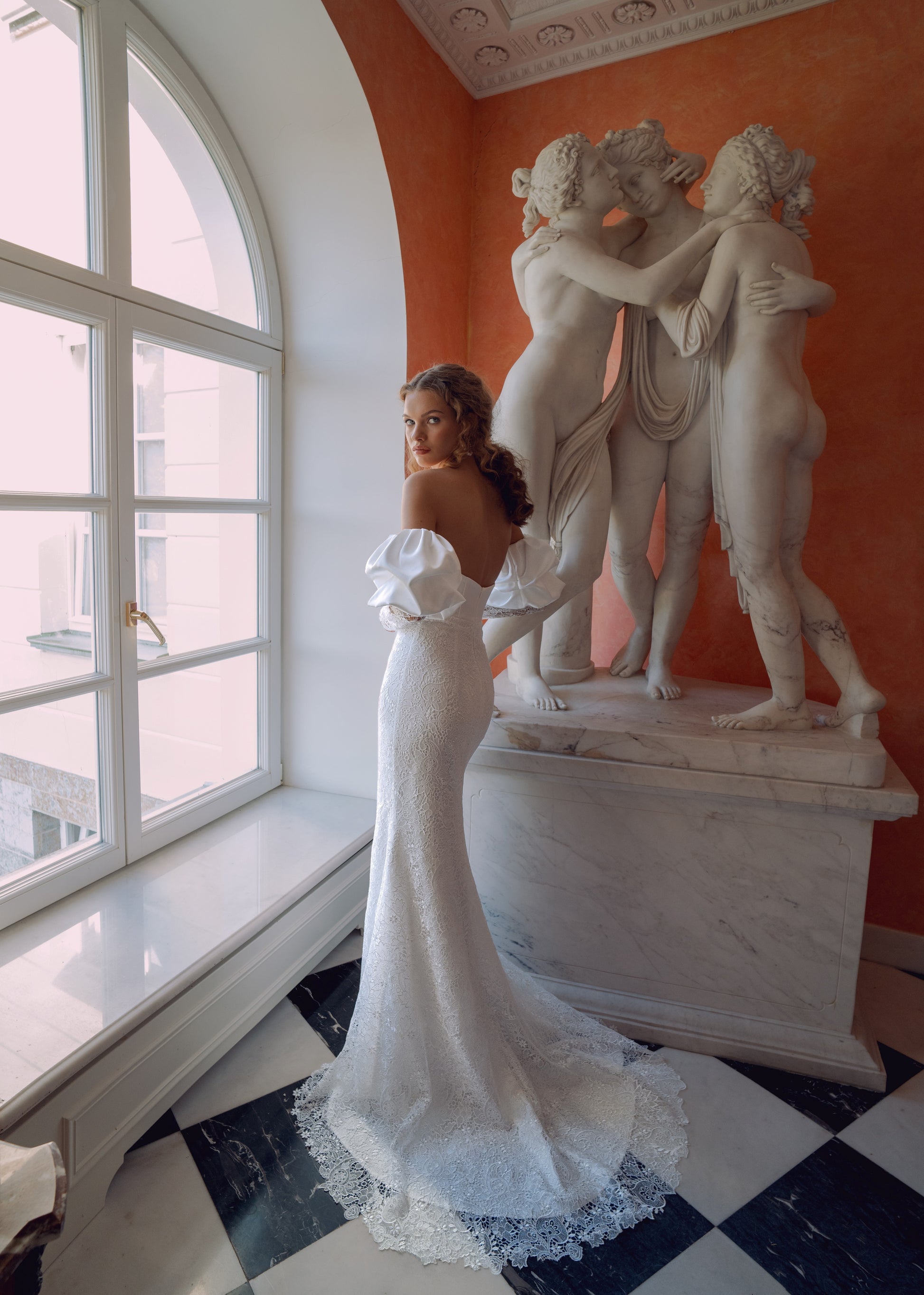Off-shoulder lace wedding gown with puffed sleeves and fitted silhouette.