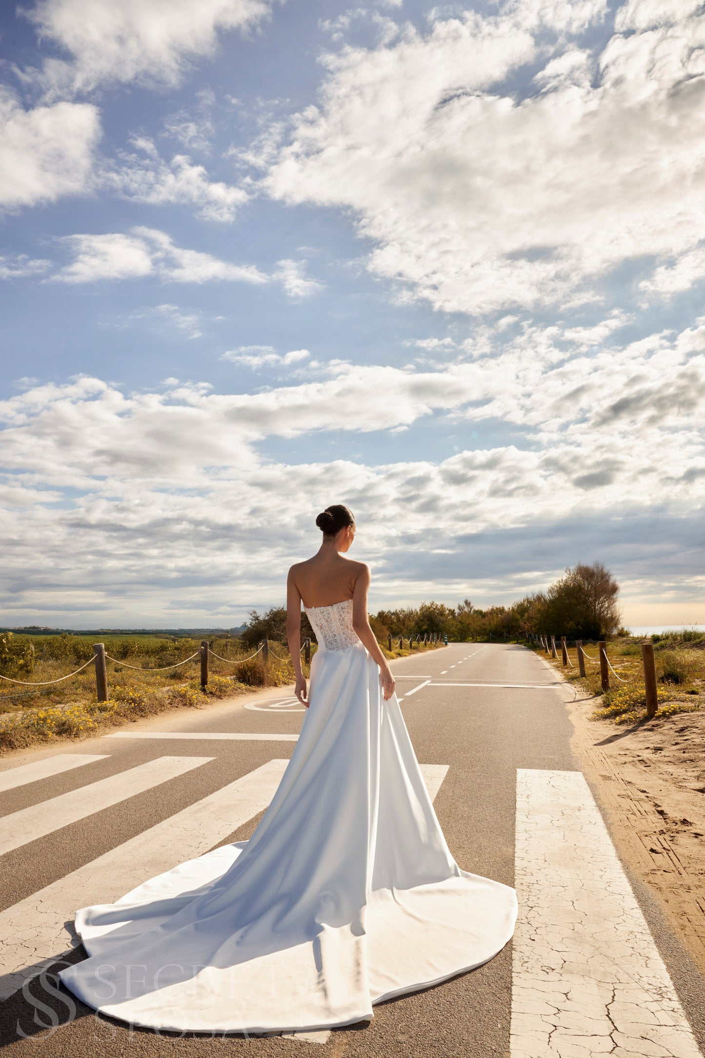 Bride in classic A-line atlas wedding gown with lace detail, V-cut neckline, drop waist, straight zip-closure back, and chapel train.