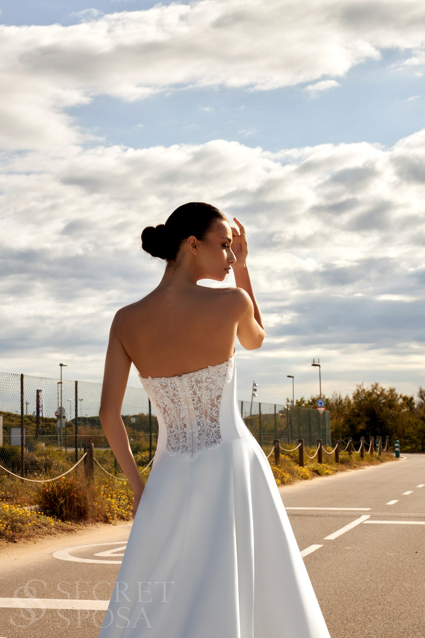 Bride in classic A-line atlas wedding gown with lace detail, V-cut neckline, drop waist, straight zip-closure back, and chapel train.