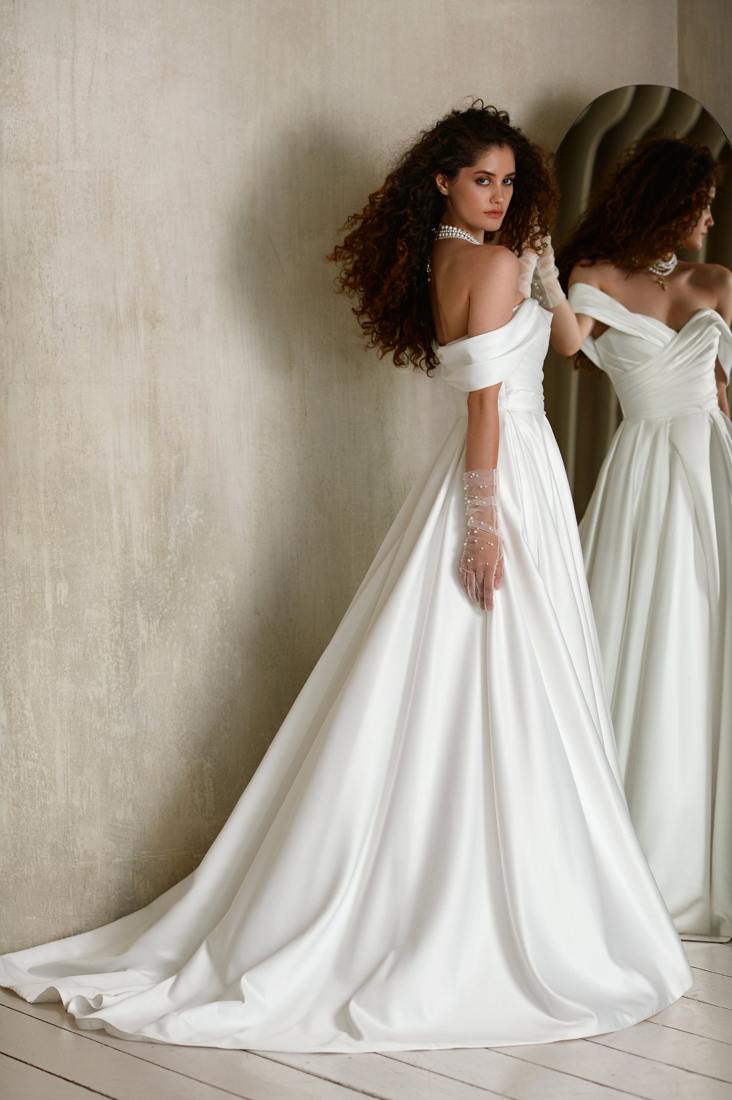 Satin A-line wedding dress with off-shoulder pleated bodice.