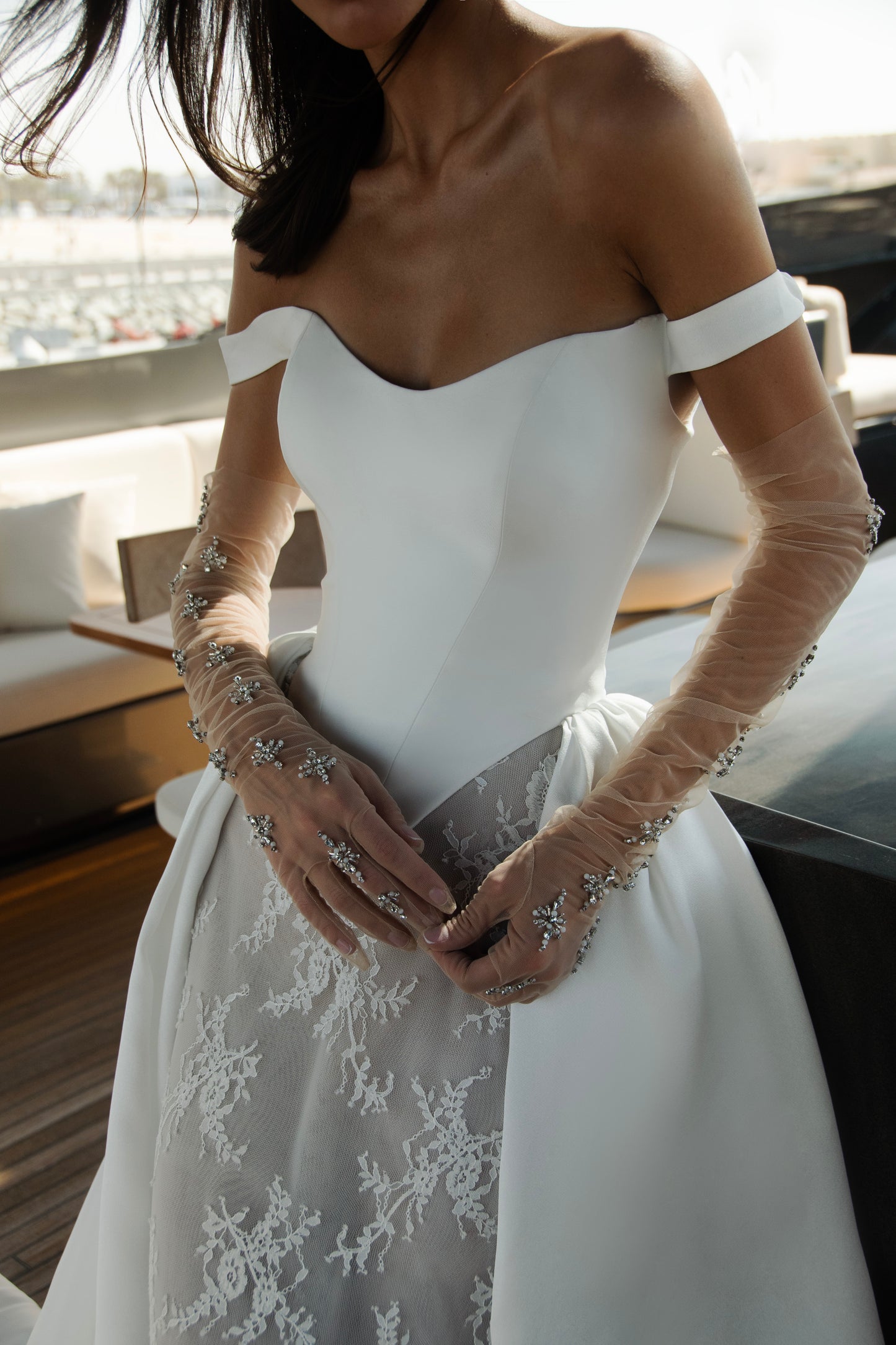 Bride wearing an off-shoulder corset wedding gown with train and optional Mikado overskirt from the Celeste Collection, photographed on a yacht.