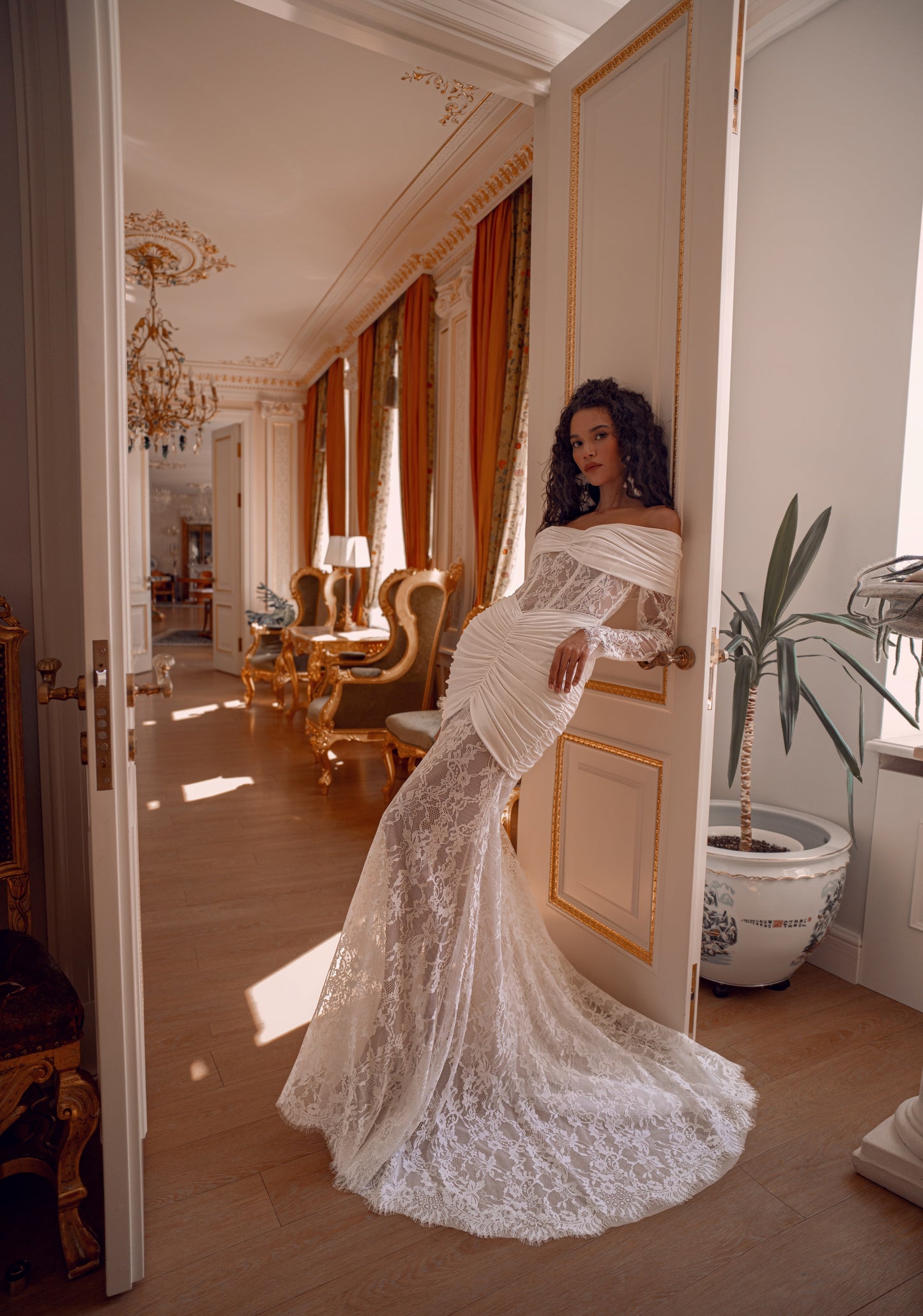 Off-shoulder lace wedding gown with draped satin details and corset bodice.