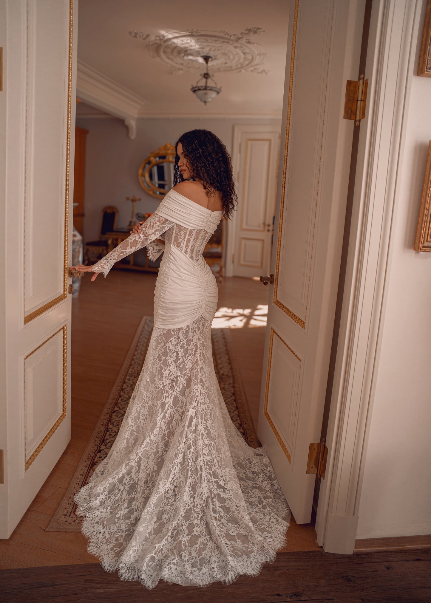 Off-shoulder lace wedding gown with draped satin details and corset bodice.