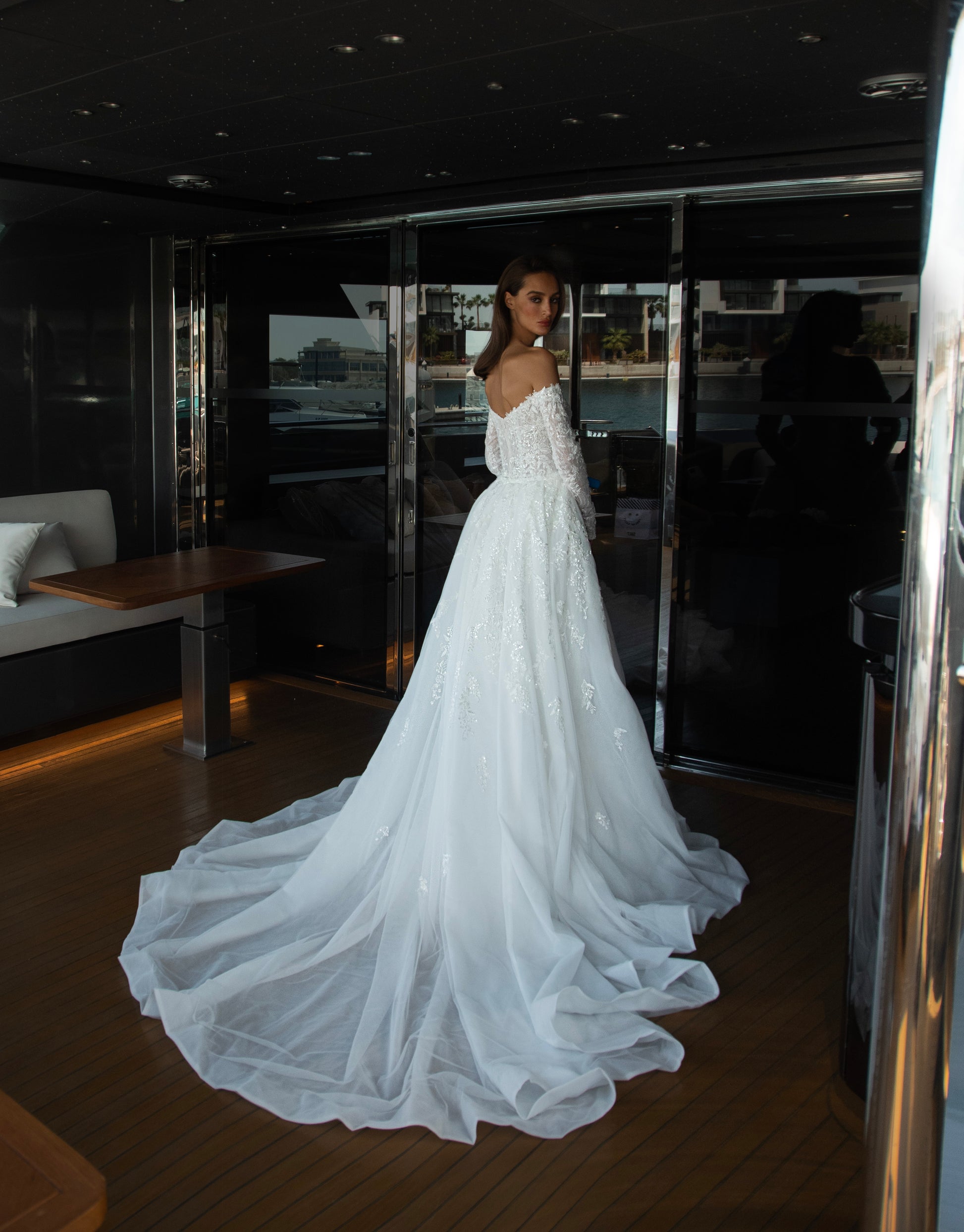 Camber off-shoulder lace wedding gown with detachable tulle overskirt. A romantic mermaid silhouette with illusion sleeves, hand-applied lace, and a sculpted corset bodice for two stunning bridal looks in one.