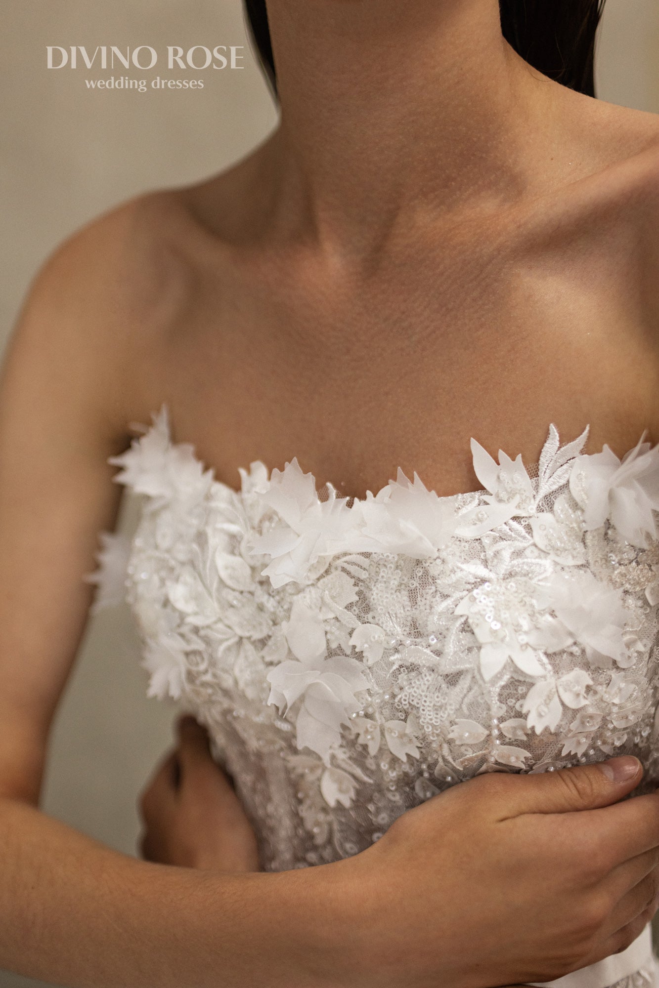 Sleeveless wedding dress with lace corset and floral details.