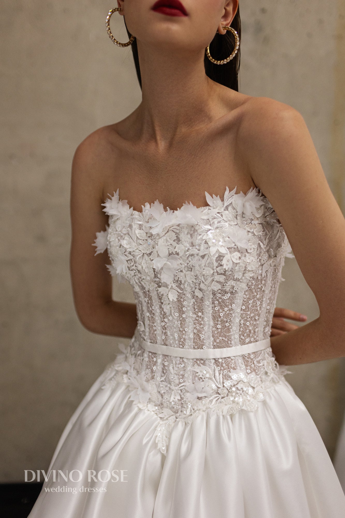 Sleeveless wedding dress with lace corset and floral details.