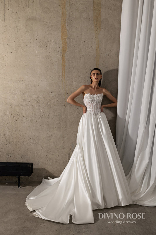 Sleeveless wedding dress with lace corset and floral details.