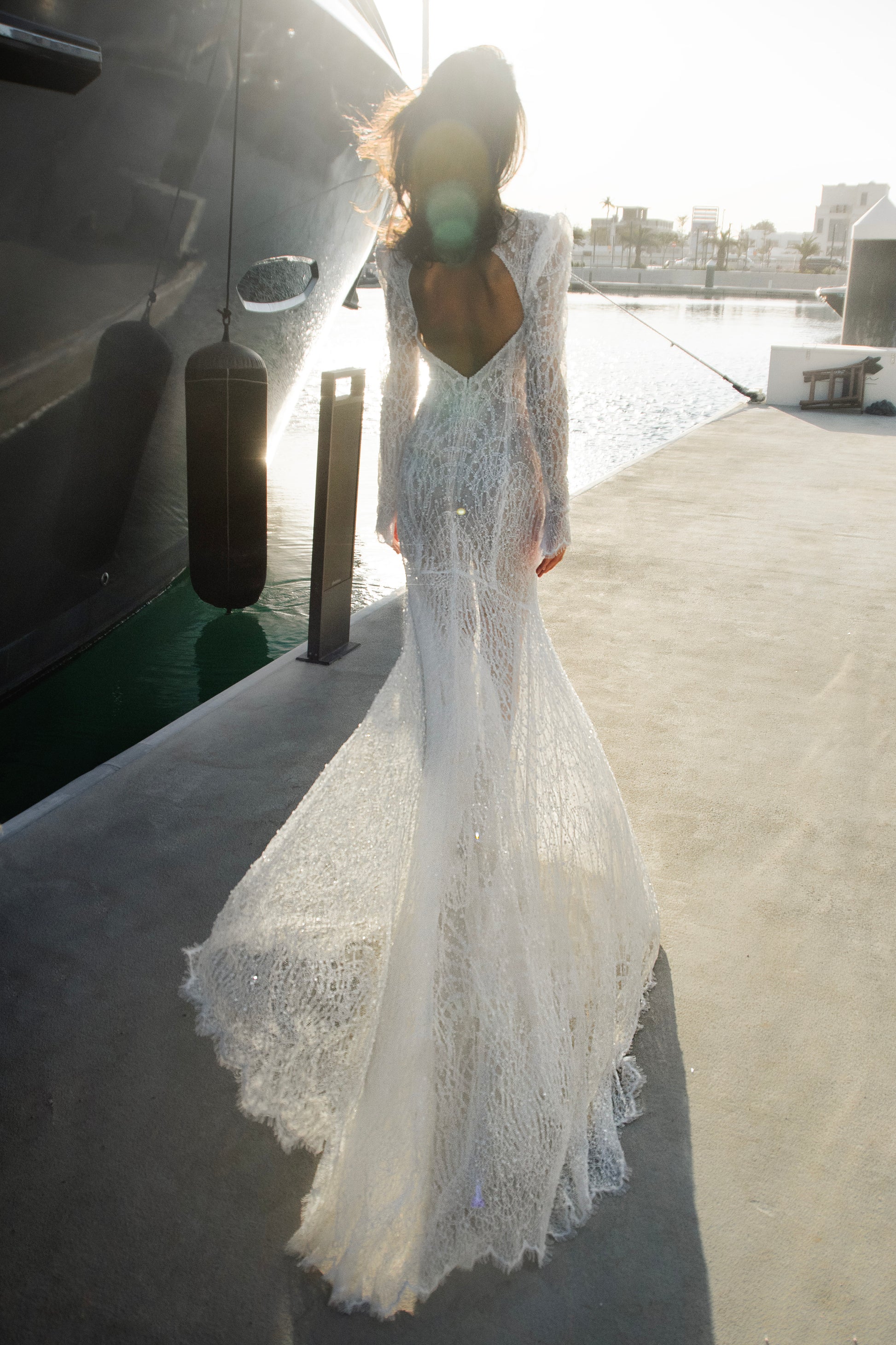 Celeste beaded lace long-sleeve sheath wedding dress with high neck and detachable tulle overskirt, open-back detail.