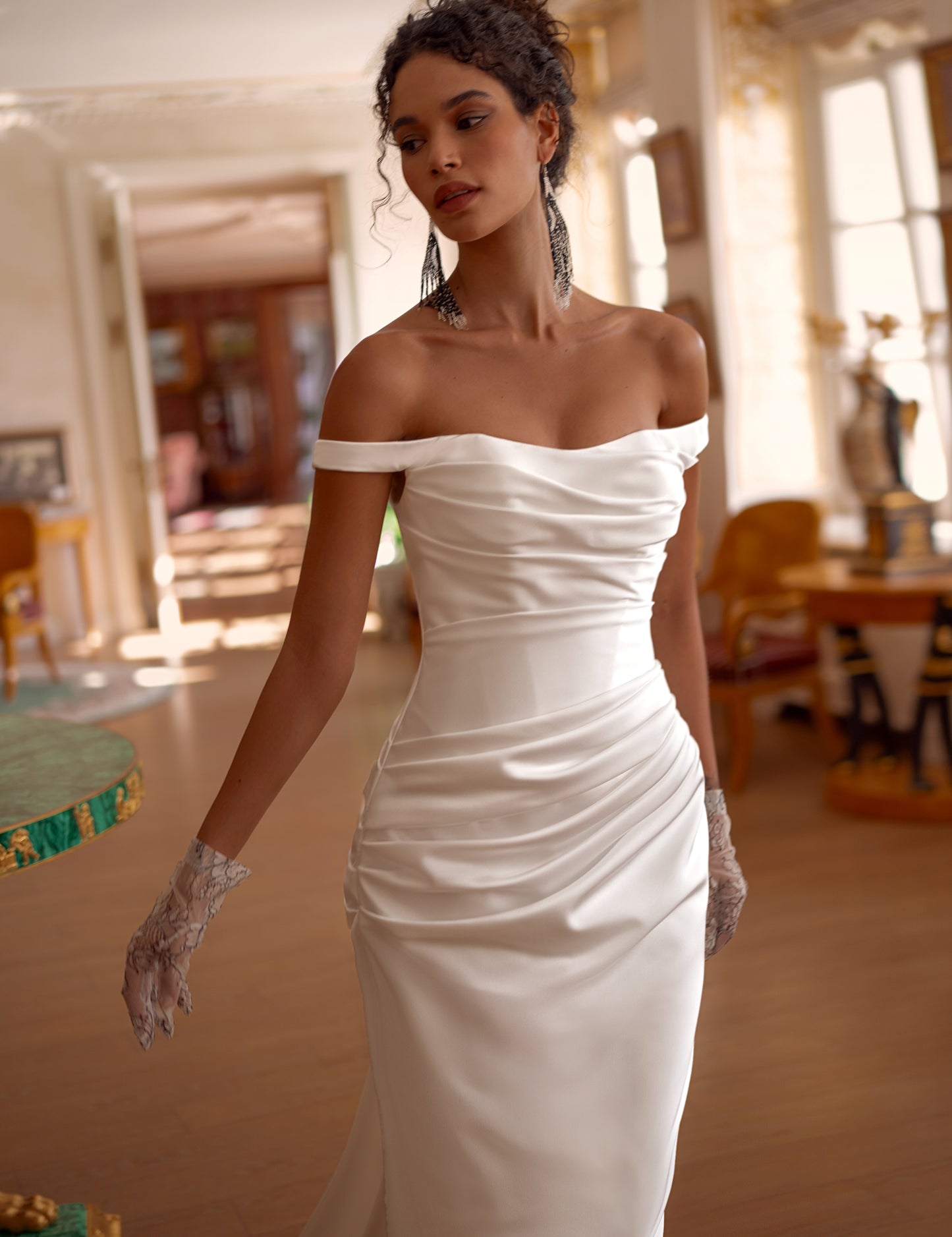 Bride in off-shoulder satin mermaid wedding gown with draped bodice, thigh-high slit, lace-up back, and sweep train.