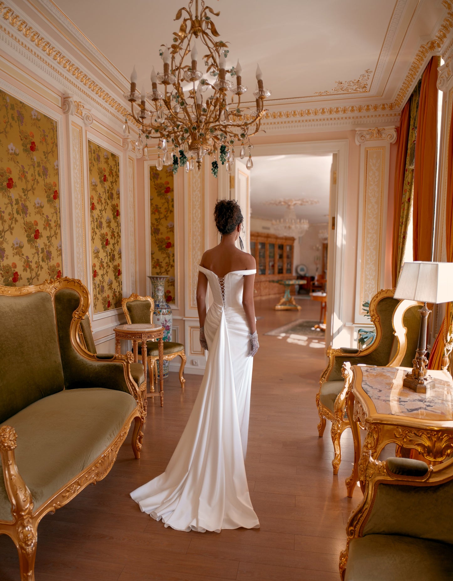 Bride in off-shoulder satin mermaid wedding gown with draped bodice, thigh-high slit, lace-up back, and sweep train.