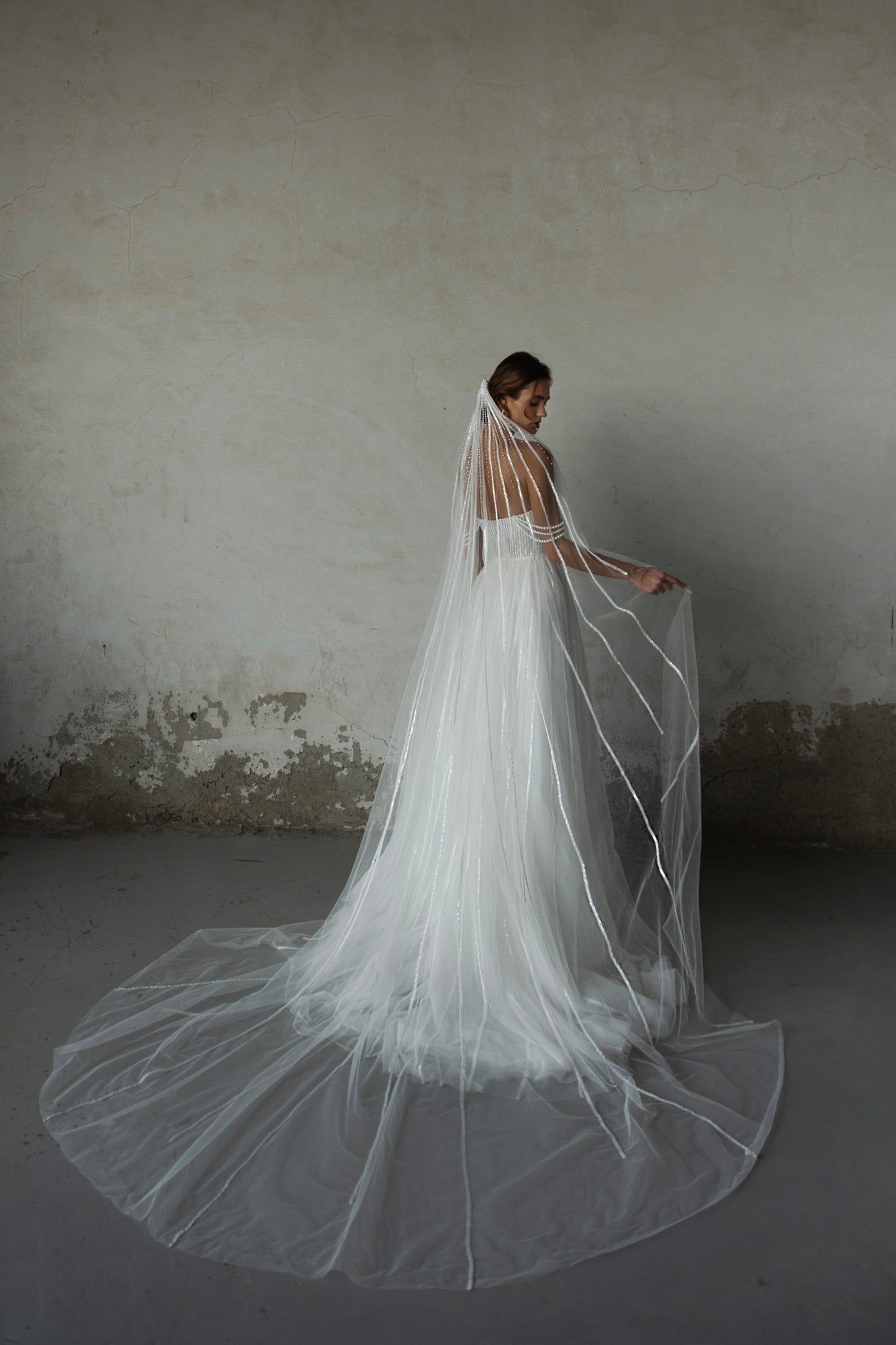 Pearl-embroidered tulle wedding dress with beaded corset bodice, detachable sheer sleeves, thigh-high slit, and flowing layered skirt