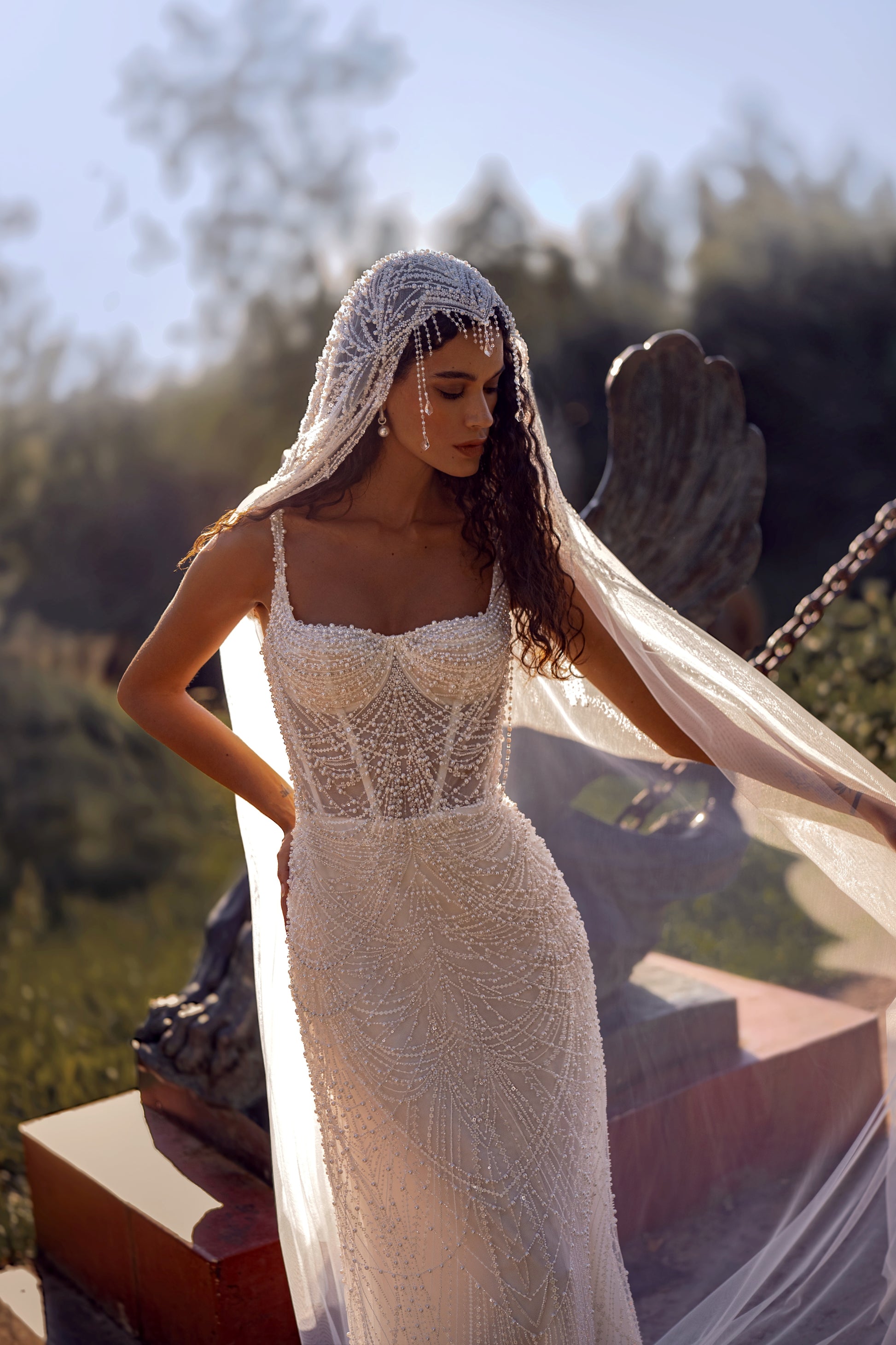 Beaded mermaid wedding gown with geometric pearl embroidery, sheer corset bodice, and elegant train.