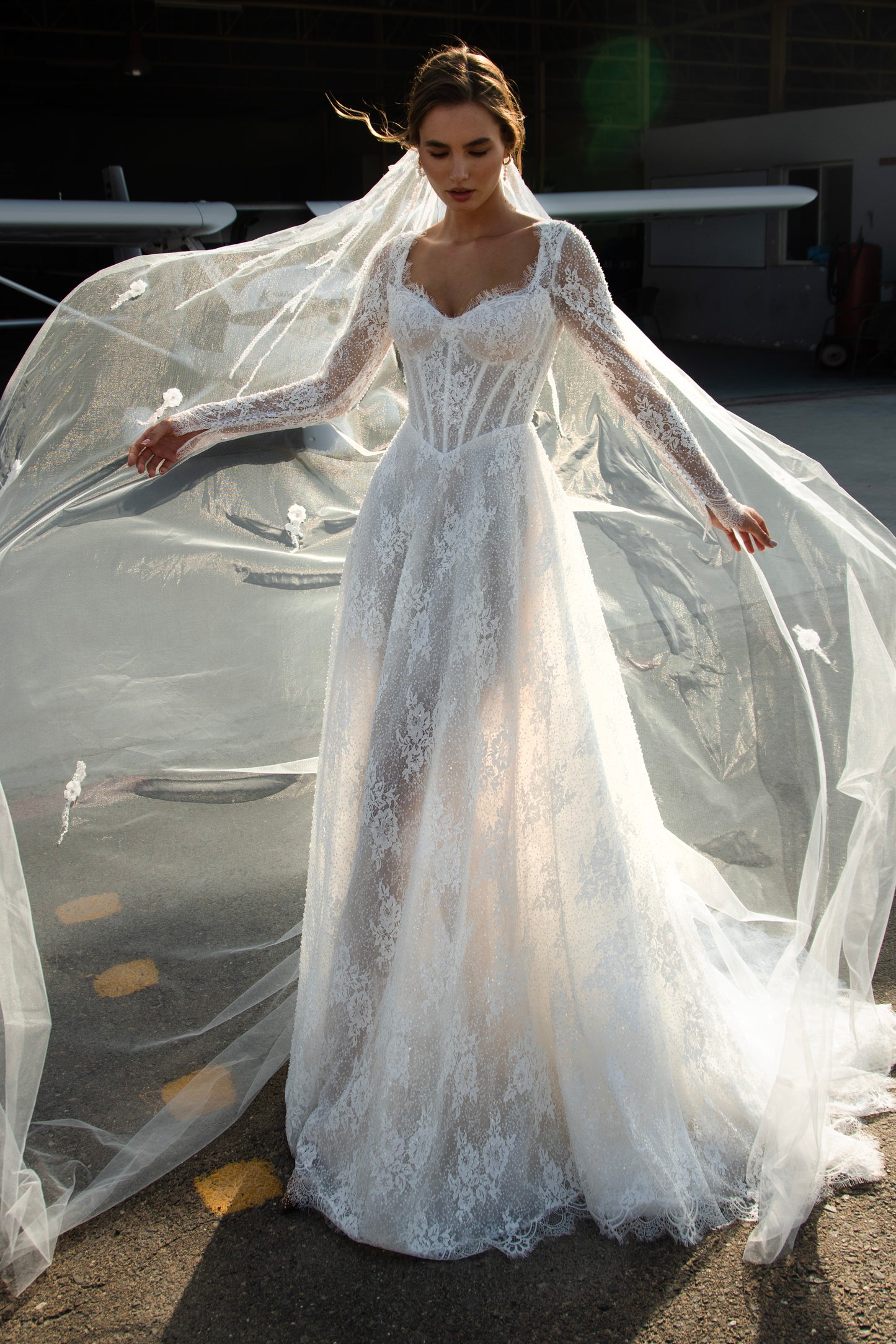 Sequin lace A-line wedding dress featuring long sheer sleeves, illusion scoop back with button-up closure, drop-down waist, and flowing court train