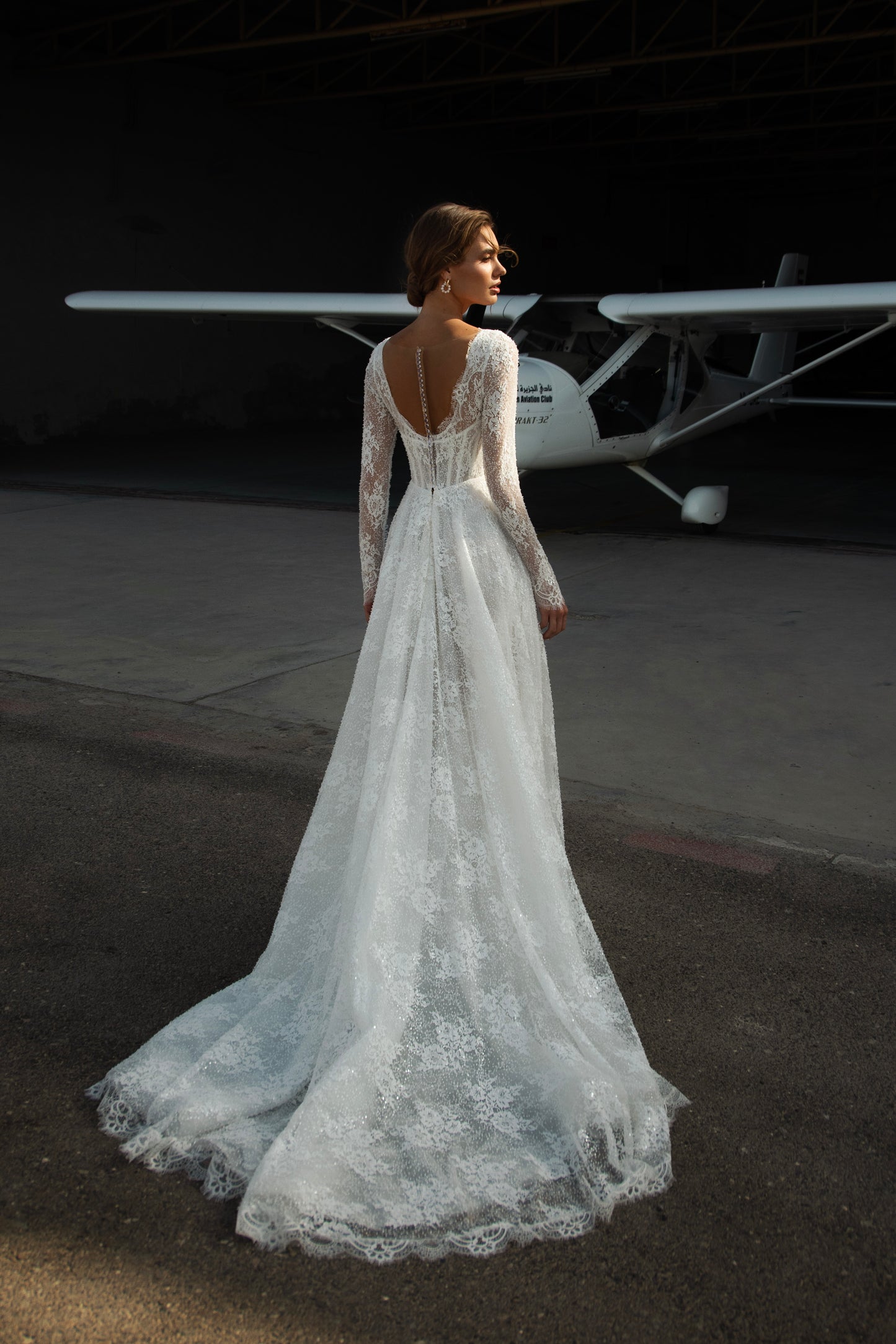 Sequin lace A-line wedding dress featuring long sheer sleeves, illusion scoop back with button-up closure, drop-down waist, and flowing court train