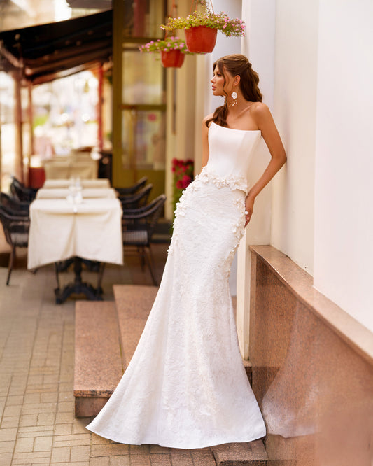 Bride wearing trumpet wedding dress with sleeveless Mikado corset, boat neckline, lace skirt, and sweep train.