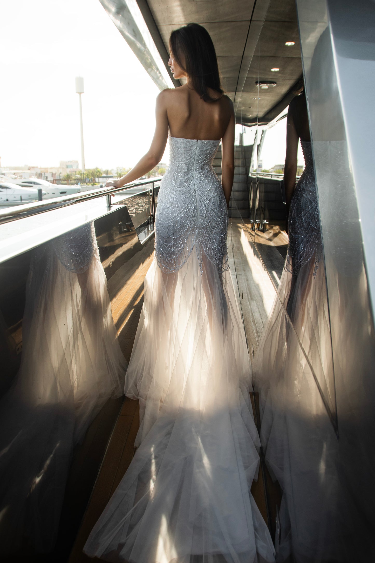 Bride wearing beaded strapless sweetheart wedding dress with removable long-sleeve illusion bolero, open back, and sheer tulle overlay.