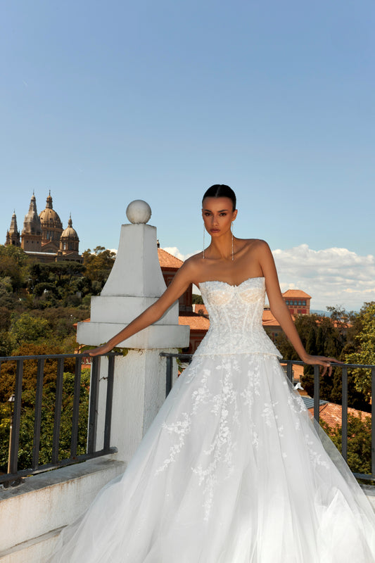 Bride in strapless sweetheart sleeveless A-line wedding gown with sequin lace corset, flowing tulle skirt, and chapel train.