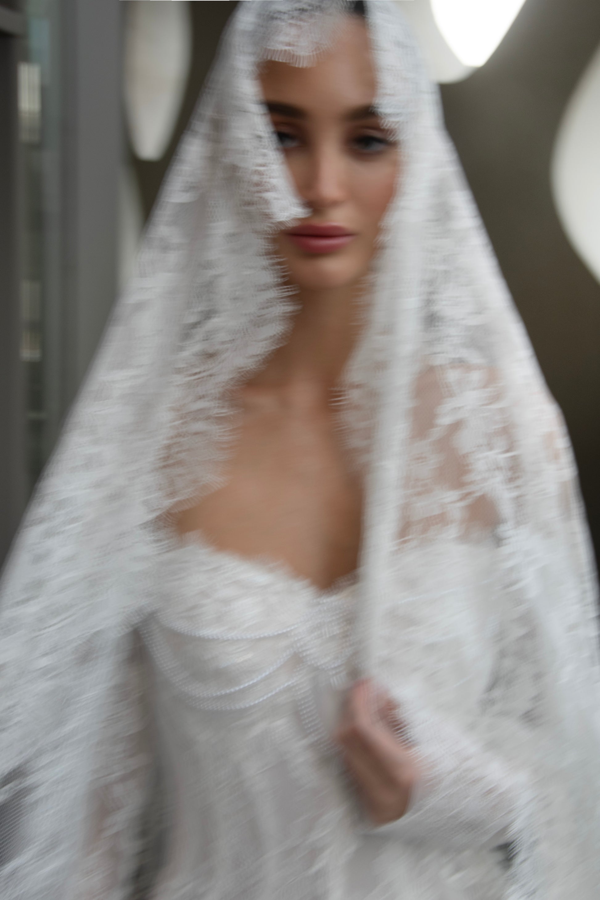 Off-shoulder lace wedding gown with long illusion sleeves, corset bodice, and chapel-length train.