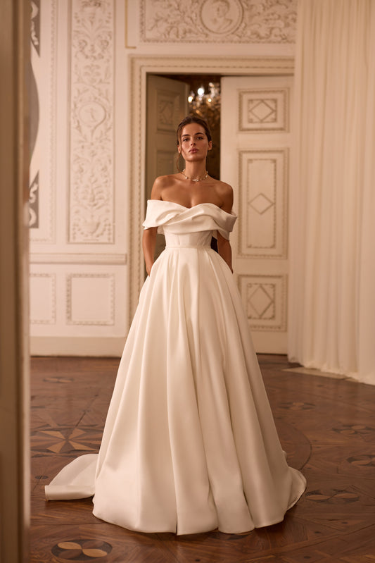 Bride wearing a two-in-one mini wedding dress with detachable mikado train and sculpted off-shoulder bodice.