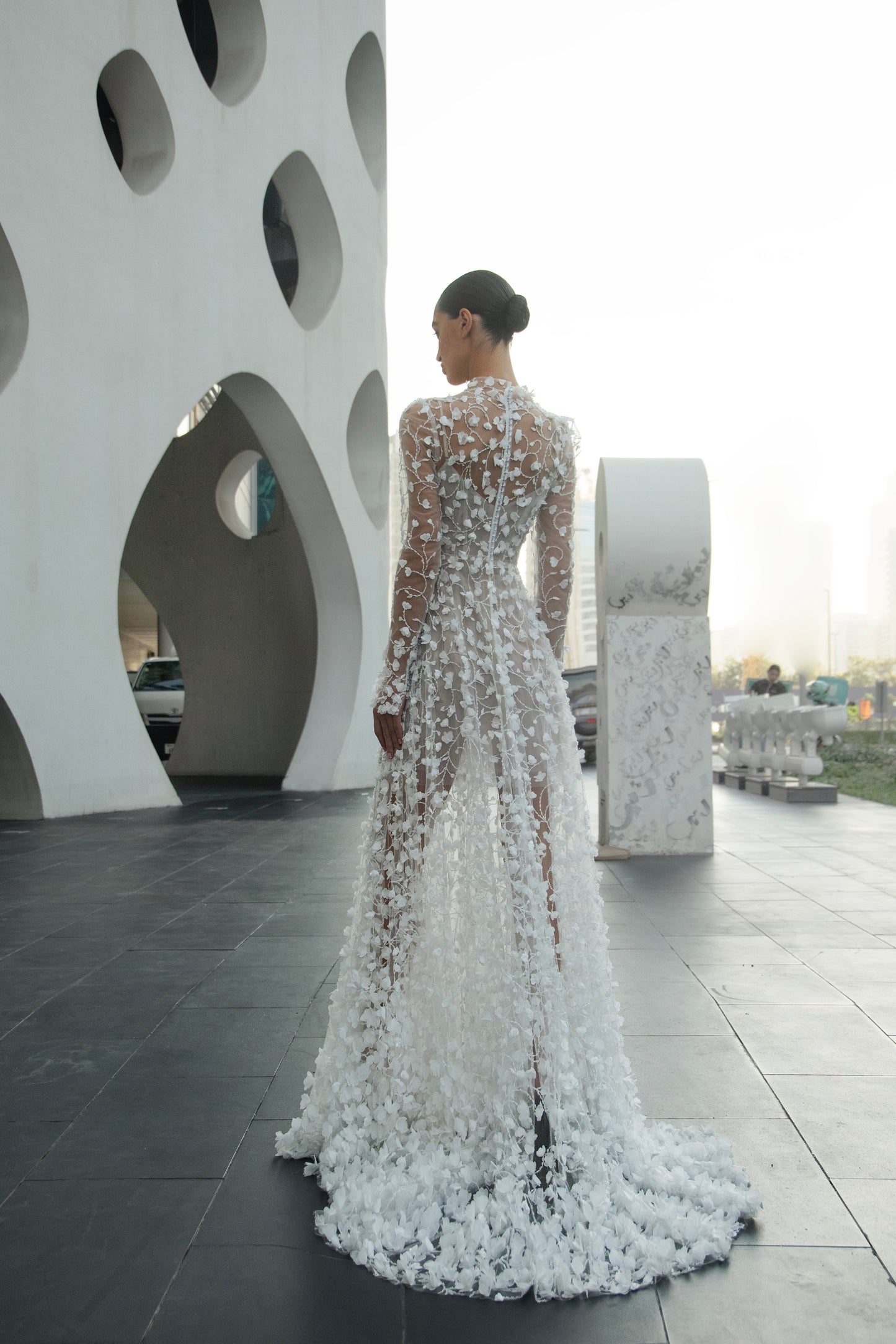 Modern 3D floral bridal mini gown with sheer long sleeves and detachable tulle overskirt.