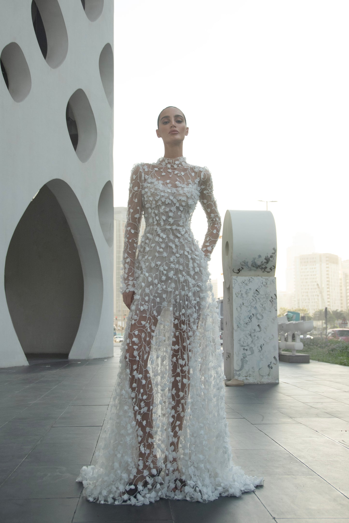 Modern 3D floral bridal mini gown with sheer long sleeves and detachable tulle overskirt.