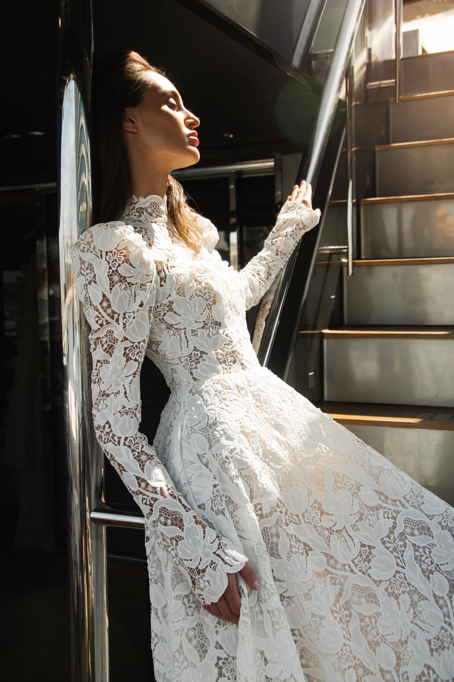 High-neck lace wedding gown with long puff sleeves, open back, and chapel-length train.