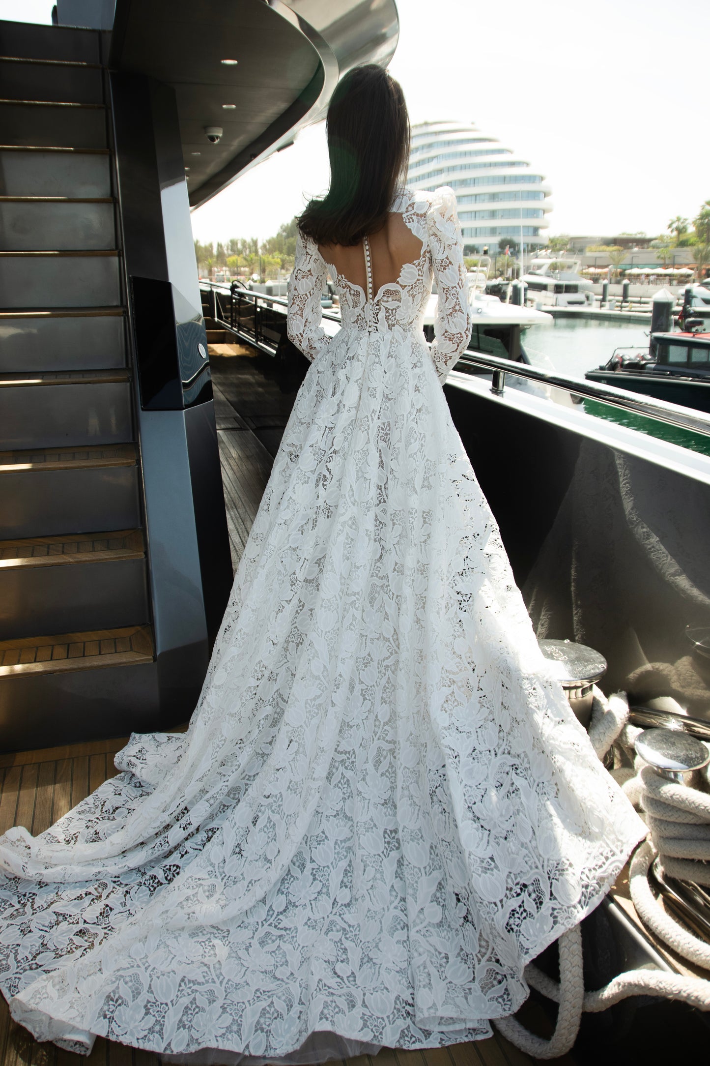 High-neck lace wedding gown with long puff sleeves, open back, and chapel-length train.