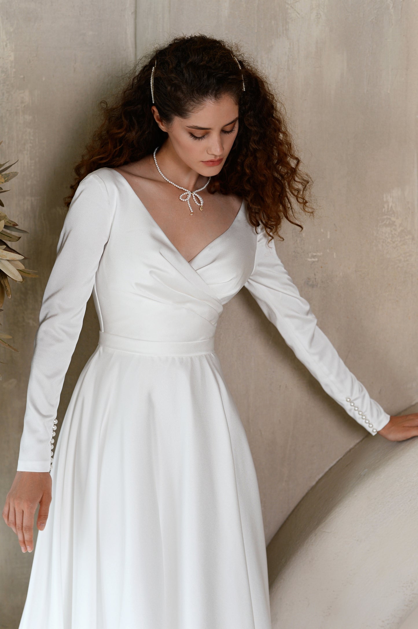 A-line satin wedding dress with long sleeves and V-neck.