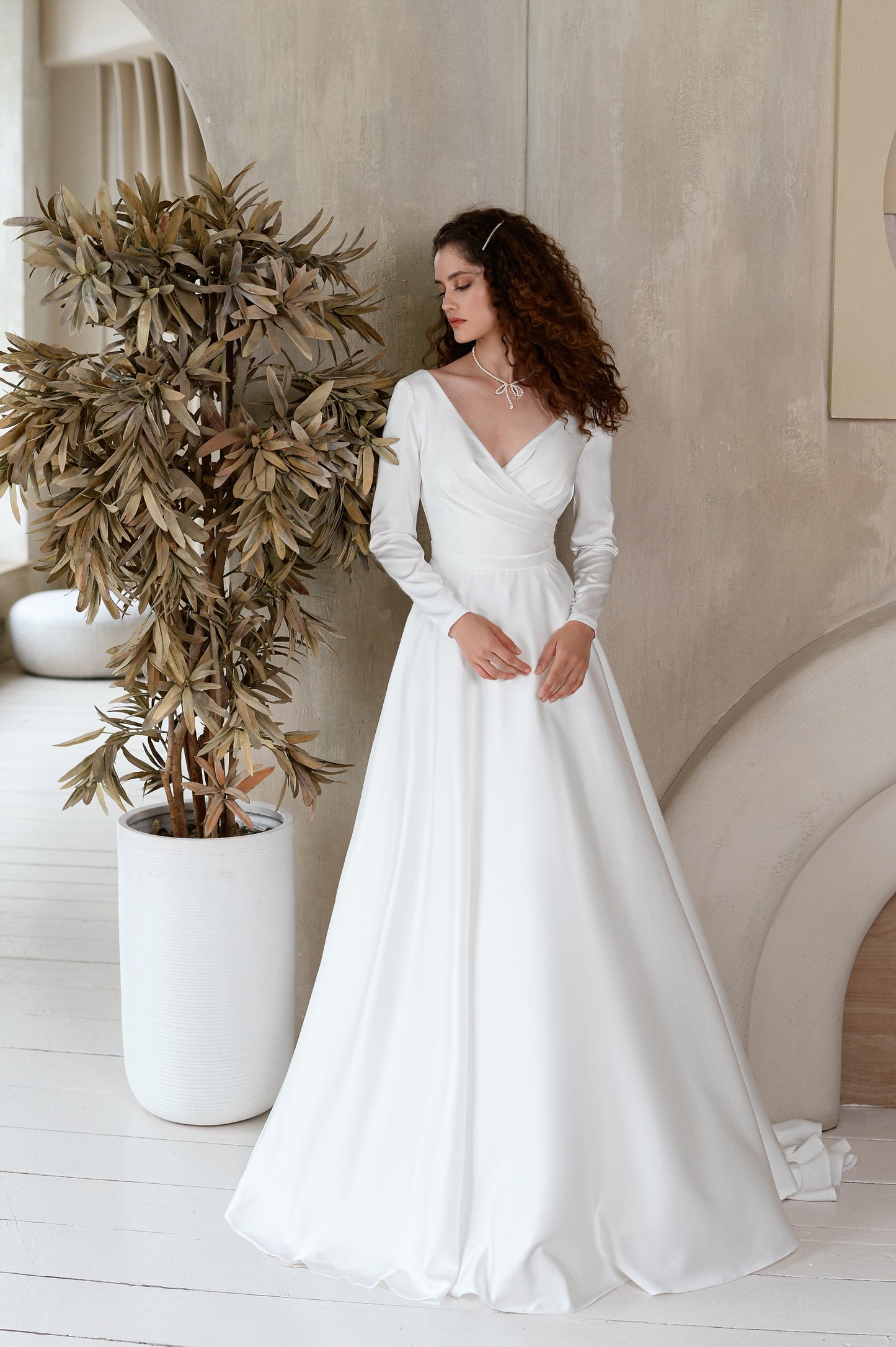 A-line satin wedding dress with long sleeves and V-neck.
