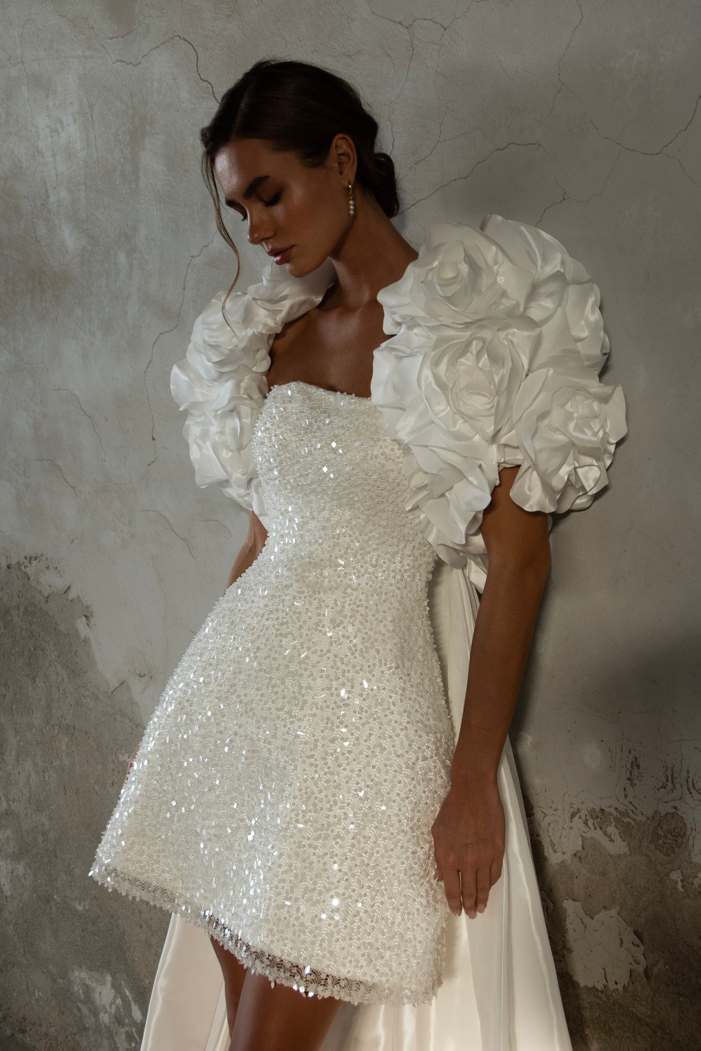 Bride wearing short beaded mini wedding dress with voluminous floral bolero and detachable satin train, photographed at sunset airfield.