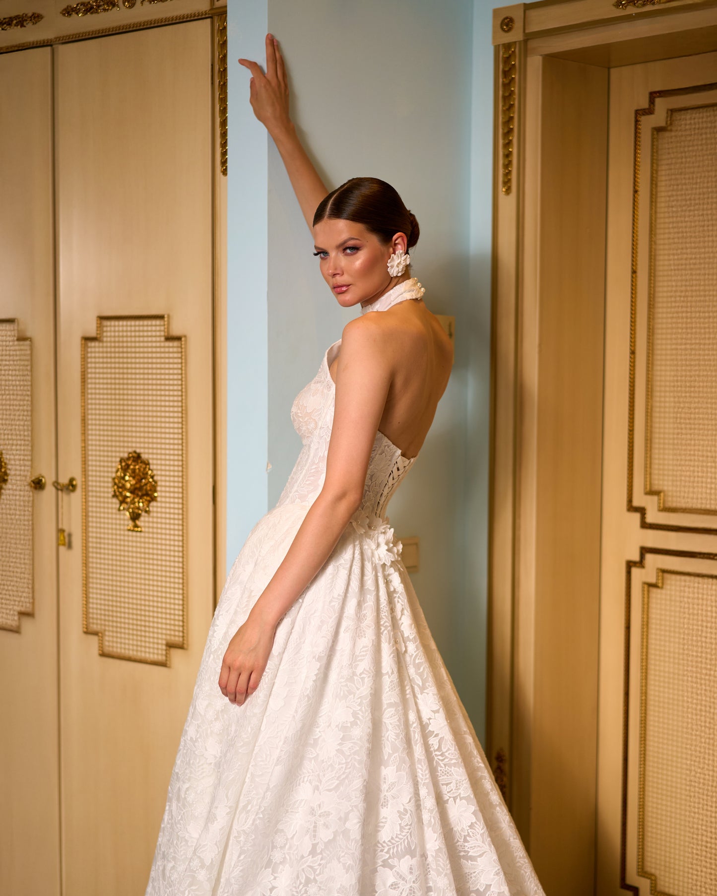 Lace A-line halter wedding dress with long removable sleeves adorned with 3D flowers, drop-down waist waspie corset, open lace-up back, and flowing chapel train for romantic bridal look