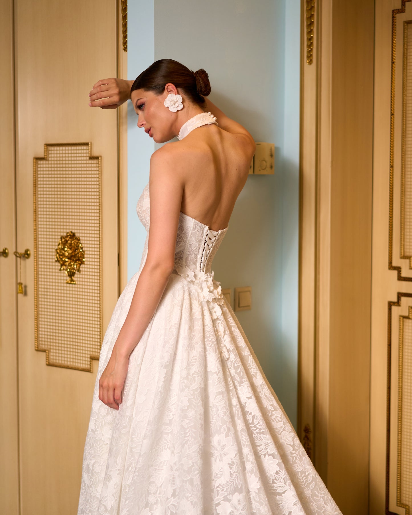 Lace A-line halter wedding dress with long removable sleeves adorned with 3D flowers, drop-down waist waspie corset, open lace-up back, and flowing chapel train for romantic bridal look