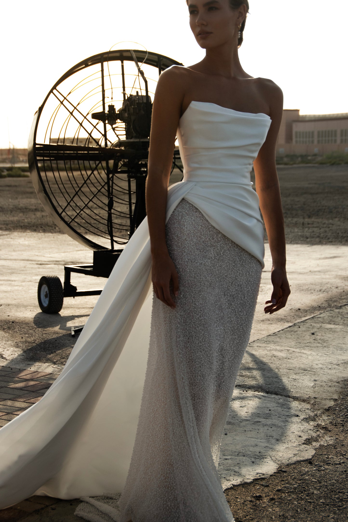 Strapless straight silhouette wedding dress with asymmetric Mikado bodice, lace skirt, zip closure, and flowing train for modern bridal style