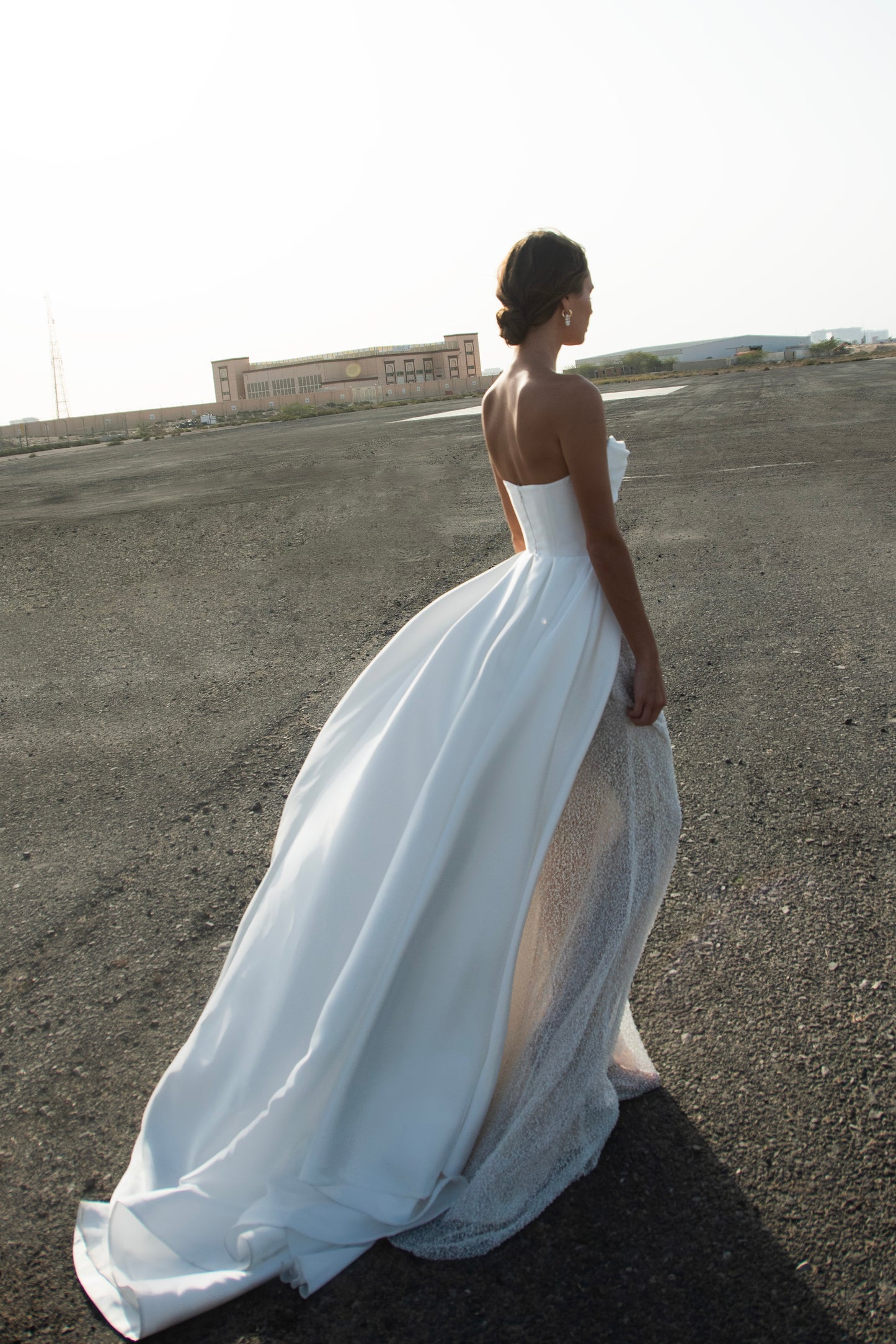 Strapless straight silhouette wedding dress with asymmetric Mikado bodice, lace skirt, zip closure, and flowing train for modern bridal style