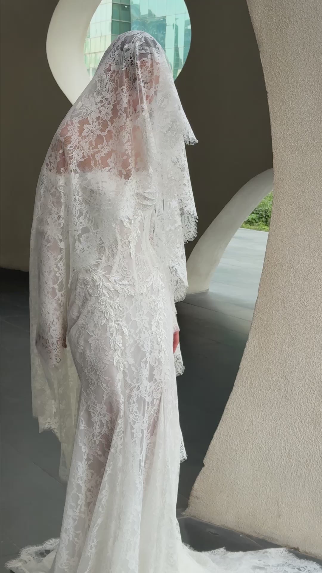 Off-shoulder lace wedding gown with long illusion sleeves, corset bodice, and chapel-length train.