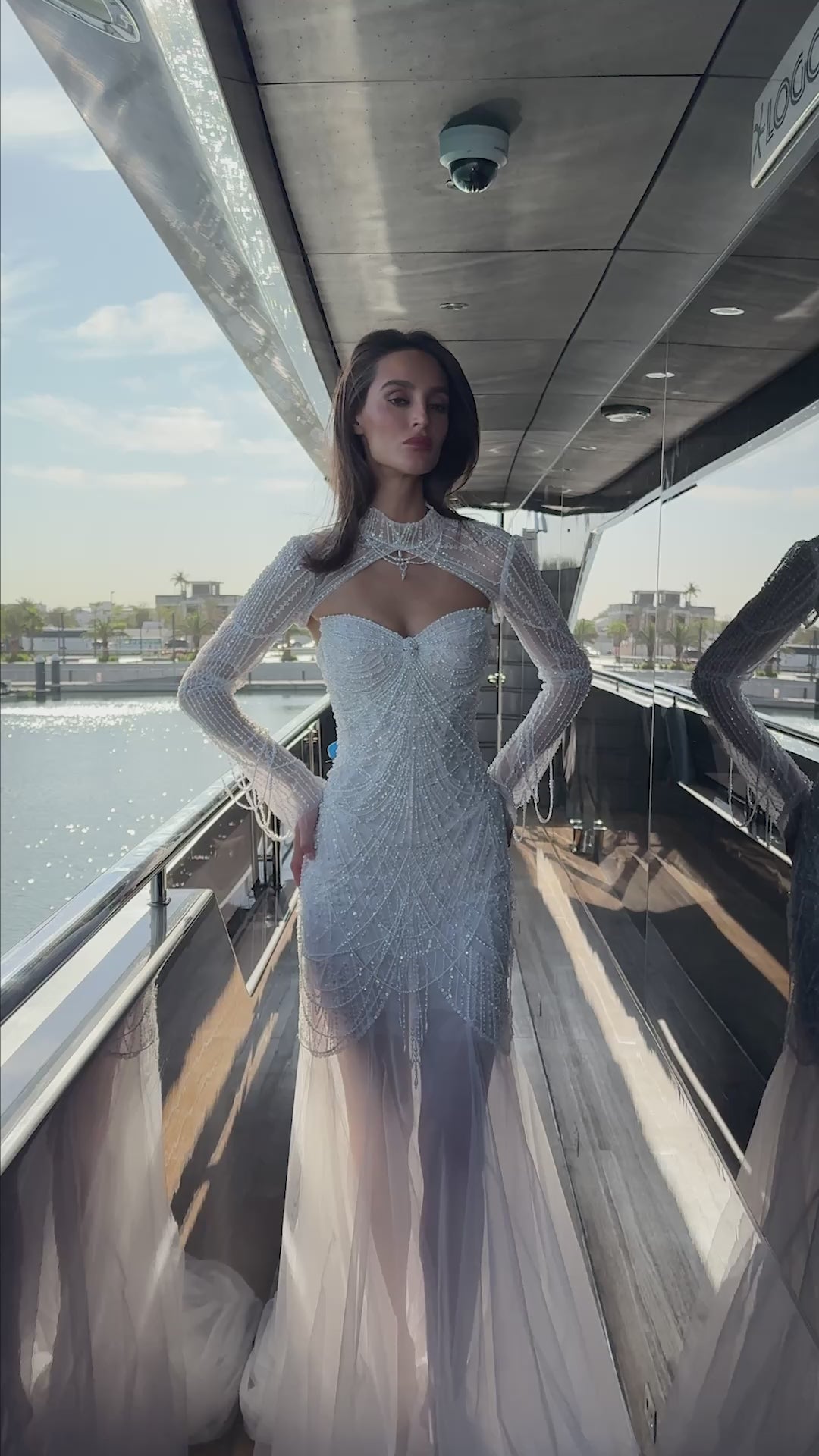 Bride wearing beaded strapless sweetheart wedding dress with removable long-sleeve illusion bolero, open back, and sheer tulle overlay.