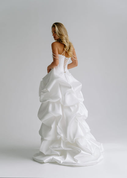 Back view of a satin corset dress with a lace-up back and a ruffled train