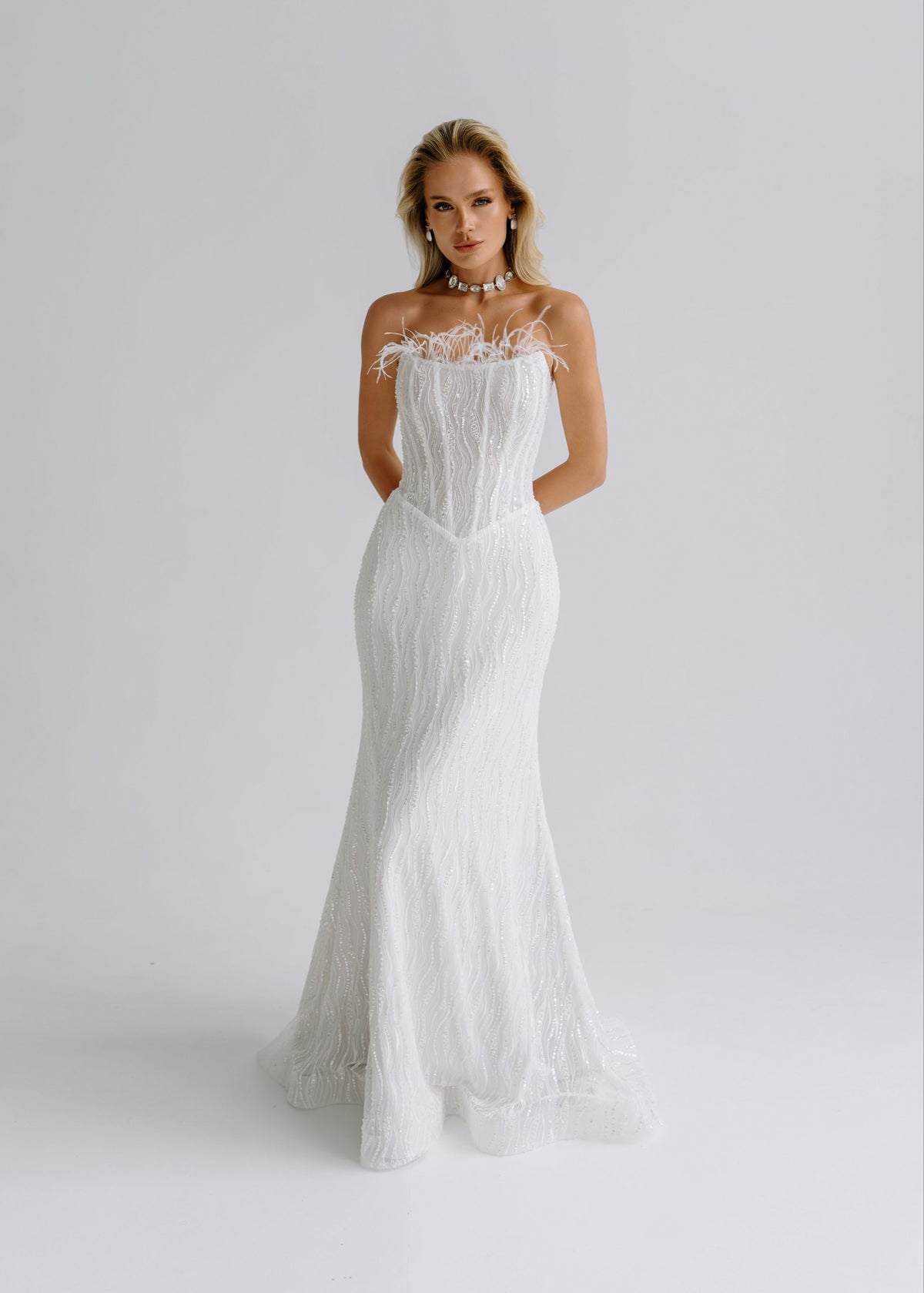 Sequin lace mermaid wedding dress with a feather-trimmed strapless neckline, front view