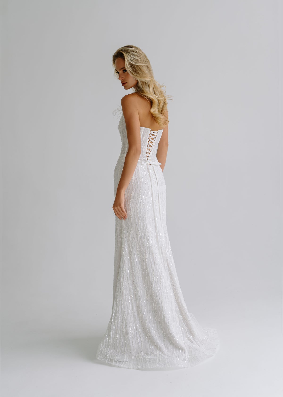 Back view of a sequin lace mermaid wedding dress with a lace-up back and a train