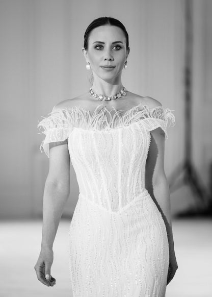 Black-and-white portrait of a feather-trimmed off-shoulder corset bodice