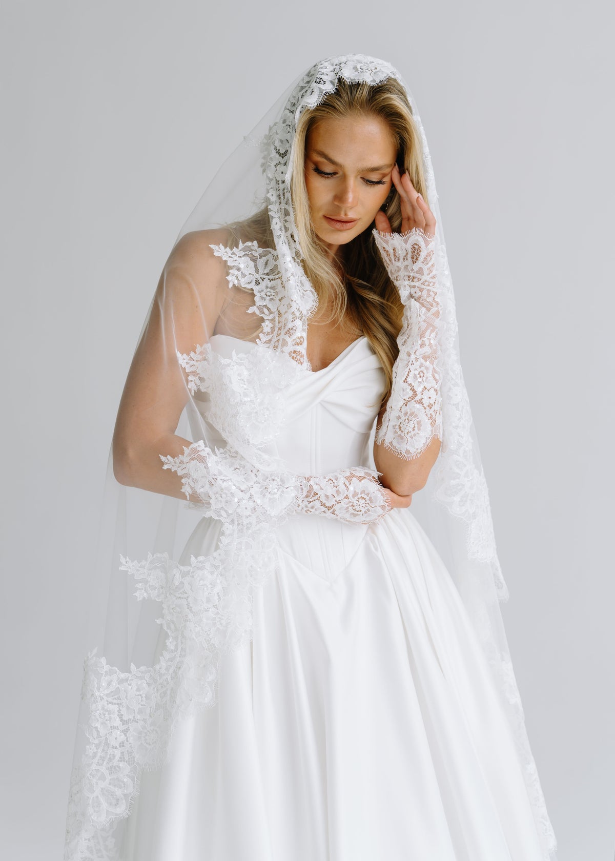 Satin bodice styled with a lace-trimmed veil and lace gloves