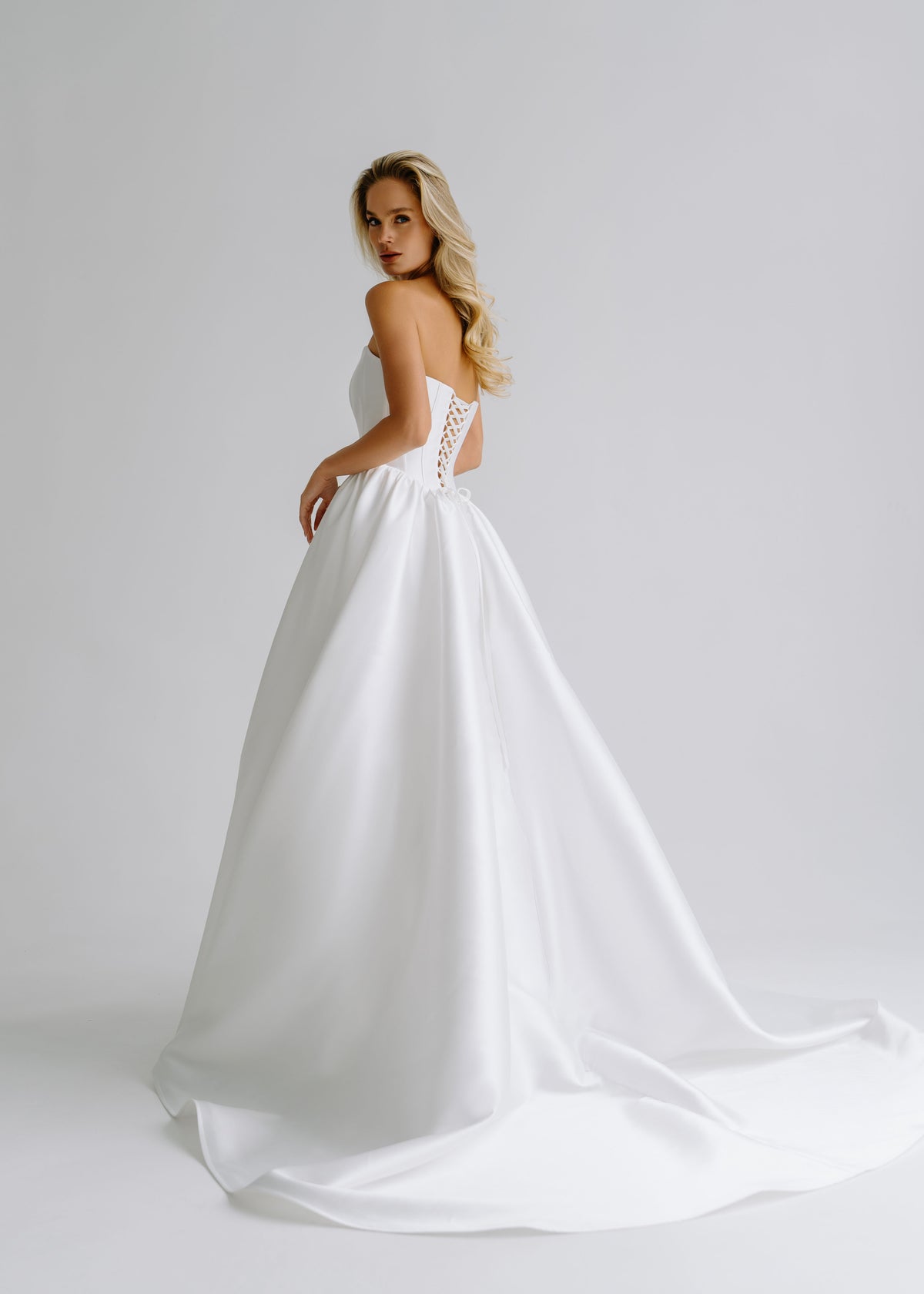 Back view of a satin wedding dress with a lace-up corset back and a train